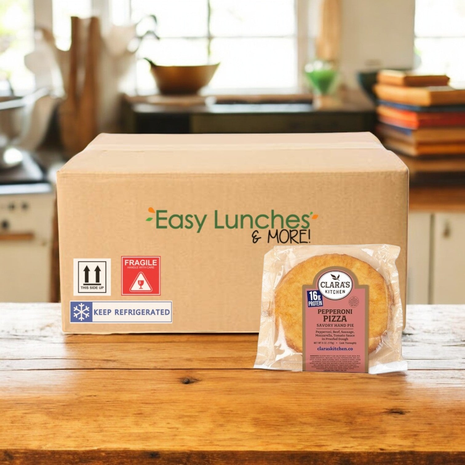 A cardboard box labeled "Easy Lunches & More!" sits on the kitchen counter with a Clara's Kitchen Pepperoni Pizza Handpie, 6 oz. nearby.