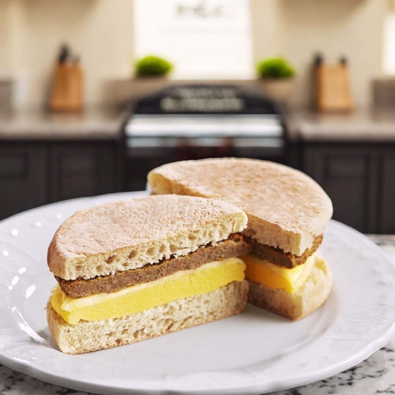 Clara's Kitchen Turkey Sausage Breakfast Sandwich, 5 oz., is halved on a white plate next to a vegetarian-friendly bean & cheese burrito. The kitchen hums softly in the background.