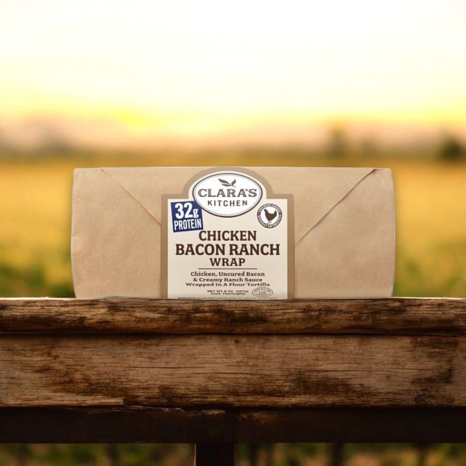 A Clara's Kitchen Individually Wrapped Chicken, Bacon & Ranch Wrap from the 8 oz. (12 Pack Case) line is placed on a wooden surface with a blurred outdoor backdrop.