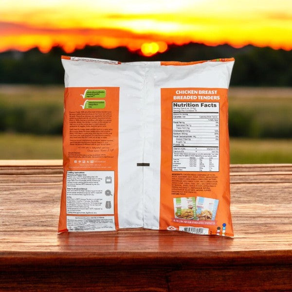 A 3 lbs package of Crescent Foods Chicken Breast Breaded Tenders, boneless and skinless, antibiotic-free, featuring nutritional details and preparation instructions sits on a wooden surface with a sunset view in the background.