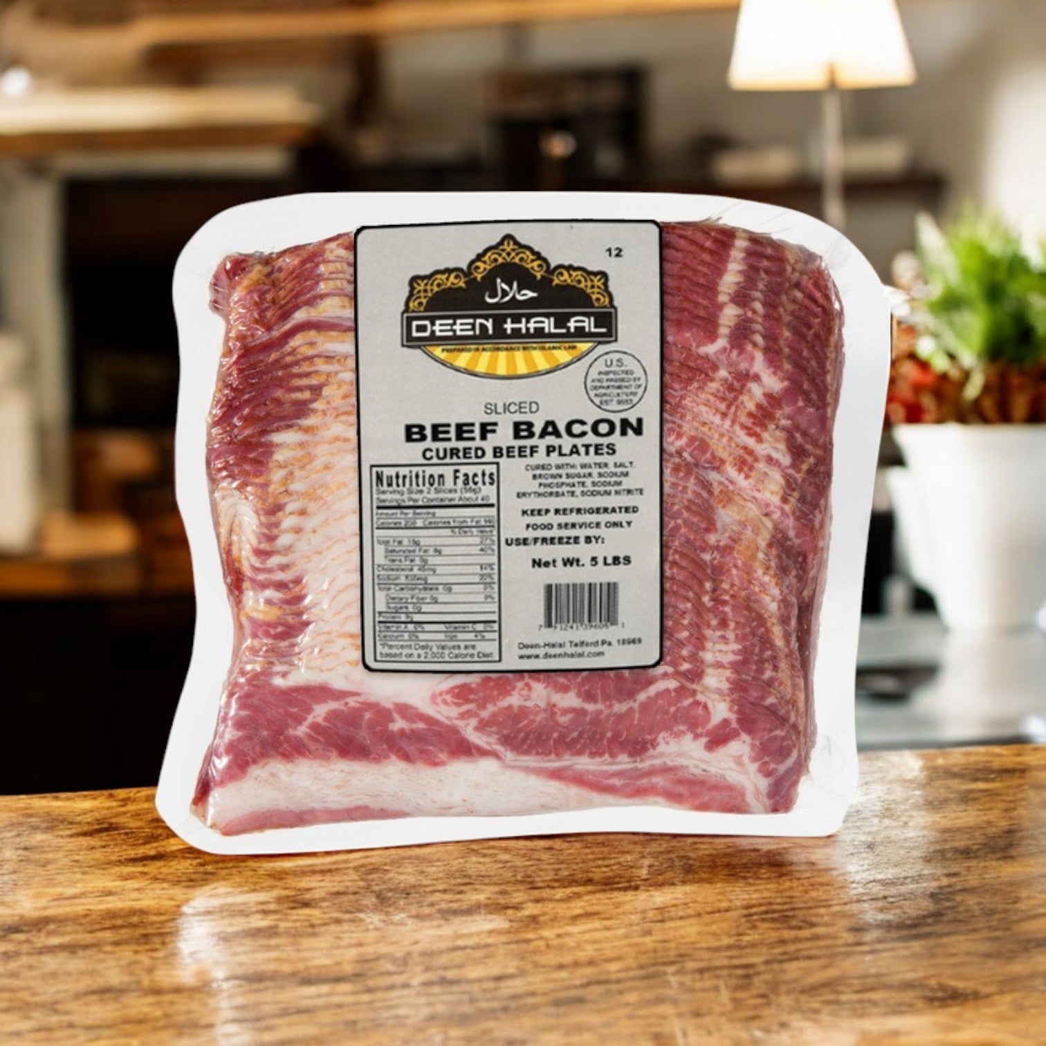 A 5 lb package of Deen Halal sliced beef bacon is displayed on a wooden surface with a blurred kitchen backdrop, highlighting its halal certification.