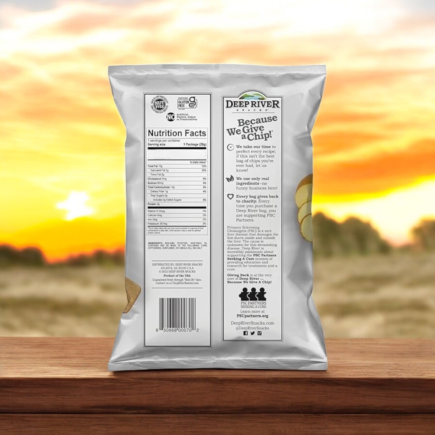 A 1-ounce bag of Deep River Snacks Original Sea Salt Kettle Potato Chips sits on a wooden surface with a sunset field backdrop. Featuring nutritional facts, a QR code, and gluten-free/kosher certifications, this snack caters to dietary needs.
