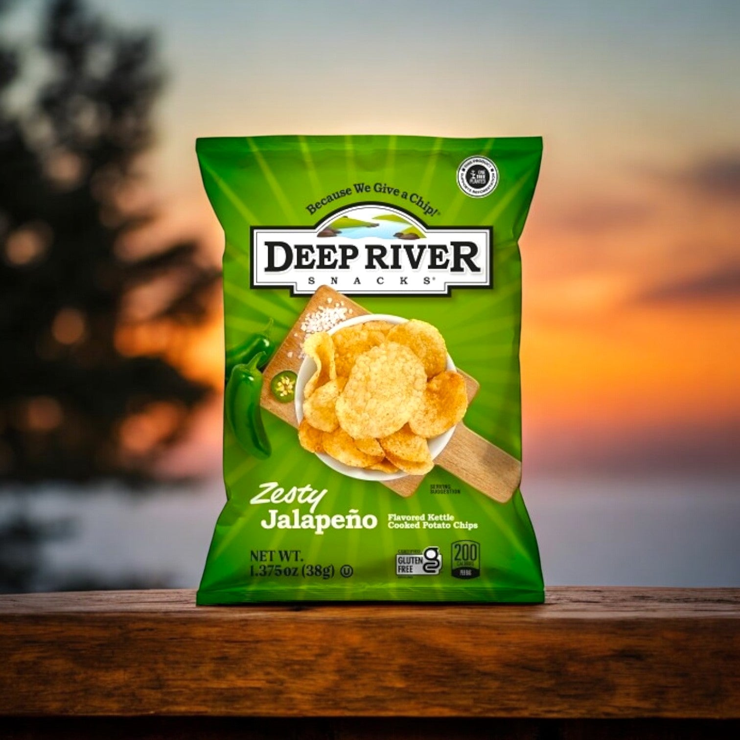 A 1.375 oz bag of Deep River Snacks Zesty Jalapeno Kettle Potato Chips, from a case of 48, rests on a wooden surface with a blurred sunset in the background.