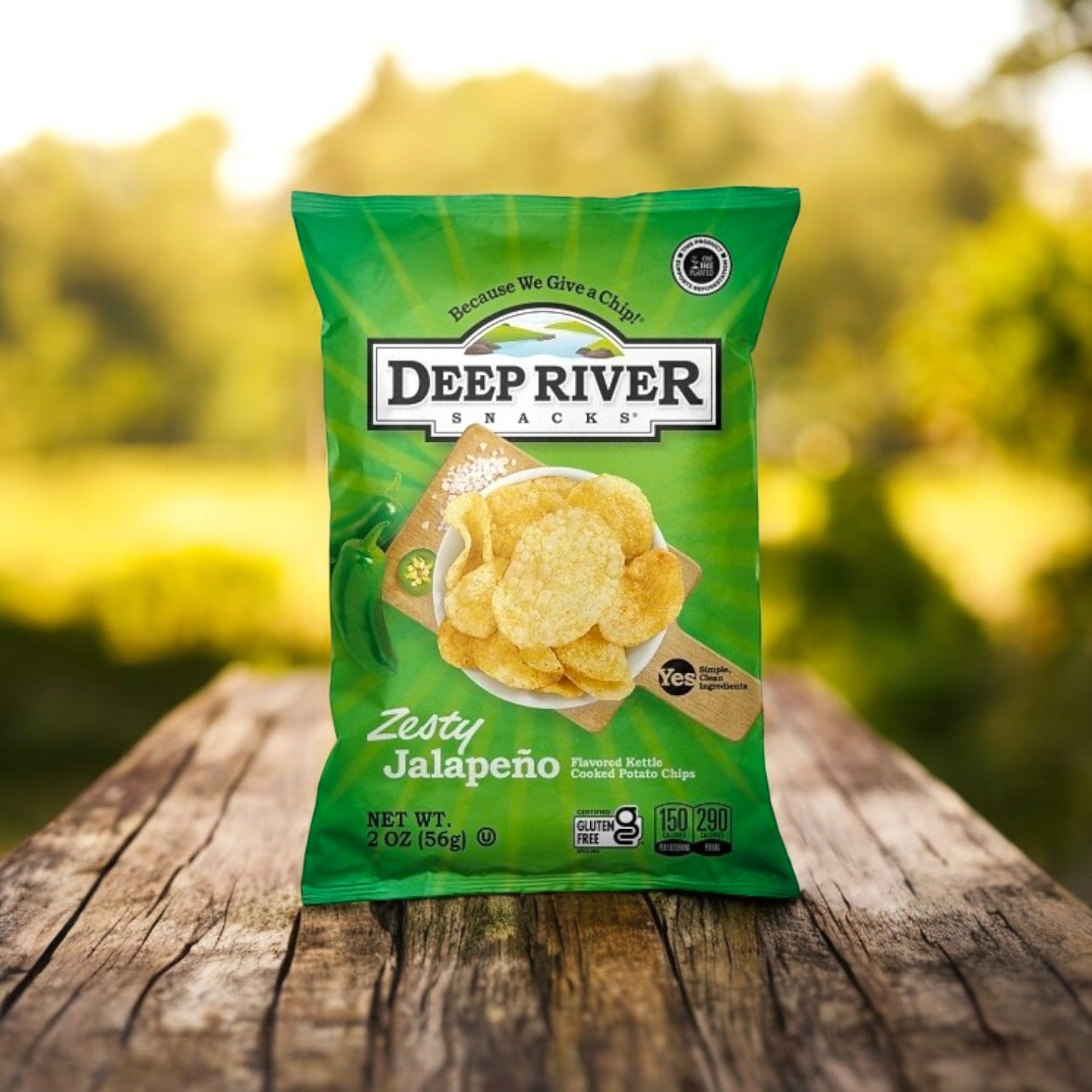 A bag of Deep River Snacks Zesty Jalapeño Kettle Potato Chips, a proudly gluten-free snack, sits enticingly on a wooden table outdoors.