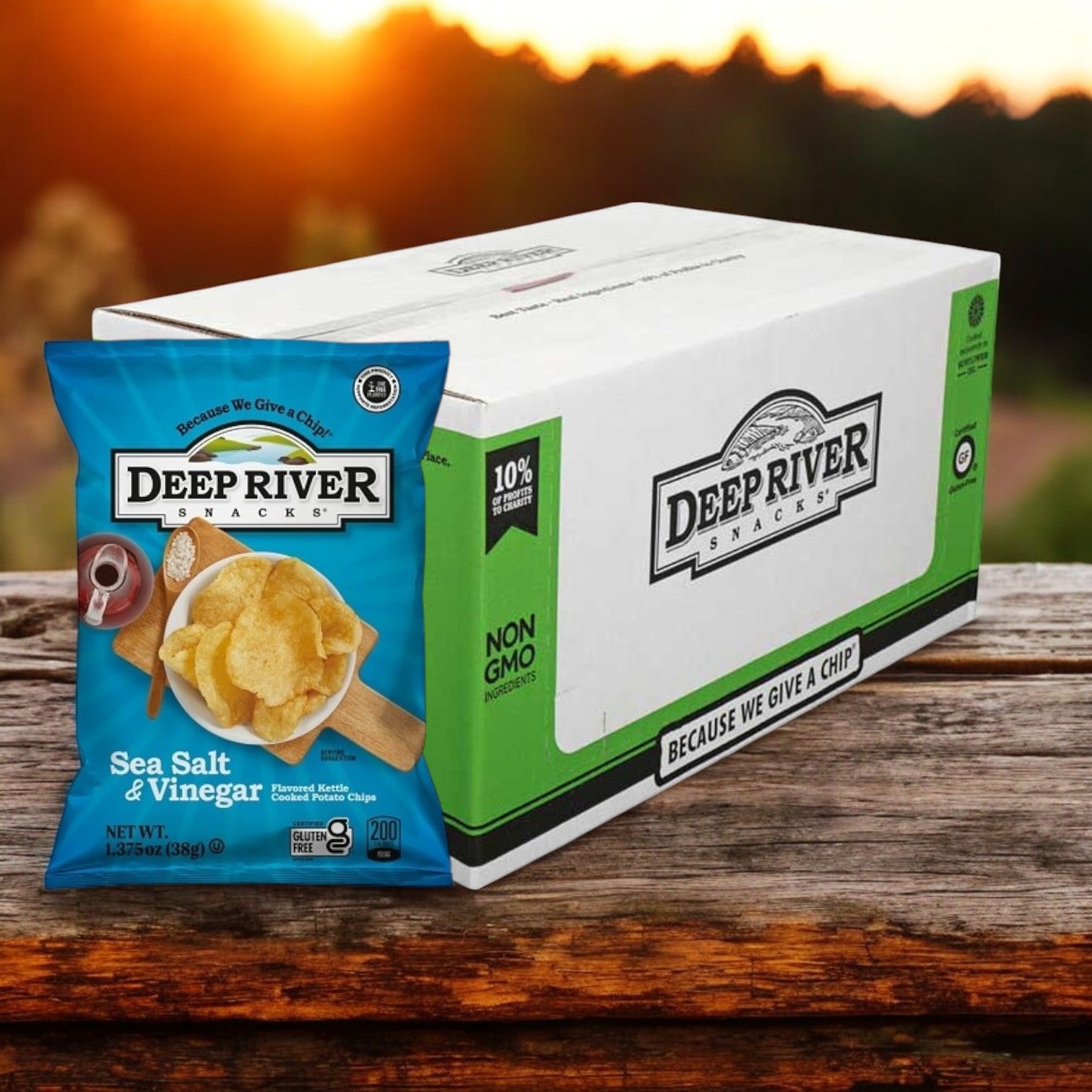 A box of Deep River Snacks Salt & Vinegar Kettle Potato Chips, 1.375 oz each, sits on a wooden table outdoors, providing a gluten-free, non-GMO snack option for your day.