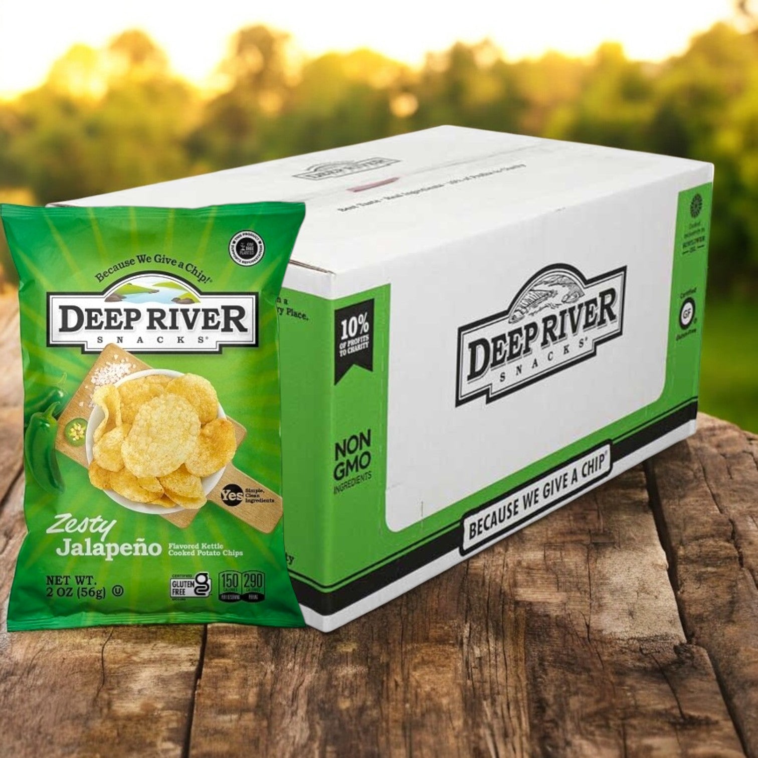 A 2-ounce bag of Deep River Snacks Zesty Jalapeño Kettle Potato Chips sits beside a Deep River Snacks box on a wooden surface outdoors, proudly displaying its gluten-free label.