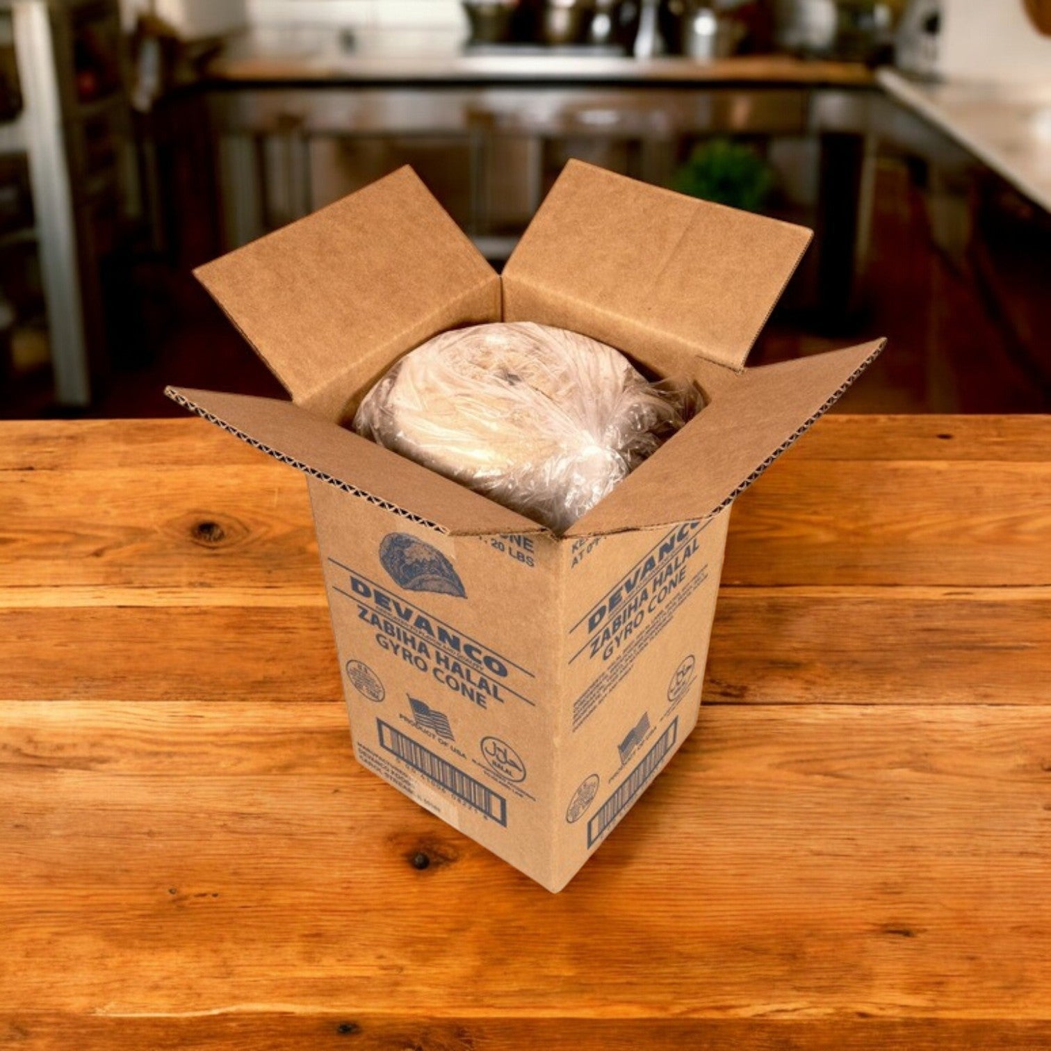 A Devanco Foods Frozen Halal Gyro Cone, wrapped and seasoned with Mediterranean spices, sits in an open cardboard box on a wooden table. Kitchen items in the background add to the authentic culinary atmosphere.