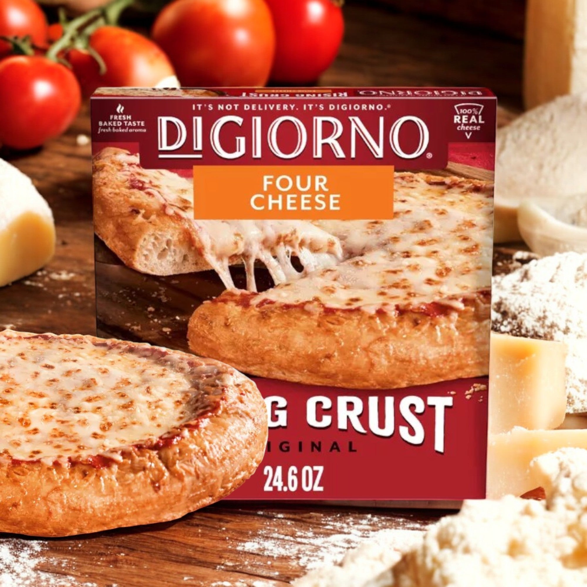 A box of DiGiorno Rising Crust Four Cheese Frozen Pizza – 24.6 oz rests among cheese, flour, and ripe tomatoes on a rustic wooden surface, offering the delicious taste made with 100% real cheese.