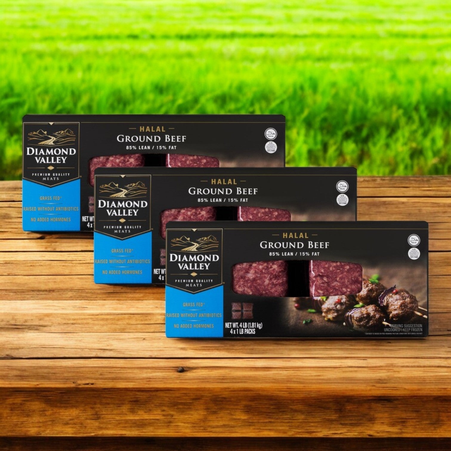 Four 1 lb chubs of New Zealand Spring Lamb's Diamond Valley halal ground beef, featuring 85% lean meat, rest neatly on a wooden surface with vibrant green grass in the background.