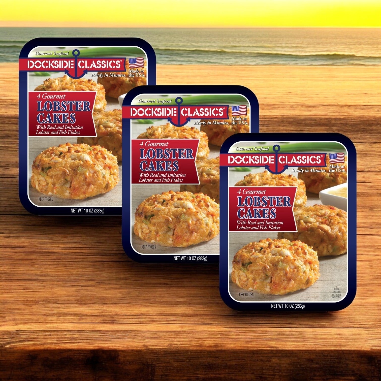 Three packs of Dockside Classics Premium Lobster Cakes, 10 oz. -3 Count, are featured by the beach. Each pack offers four gourmet cakes made with quality ingredients, ensuring a memorable seafood experience.