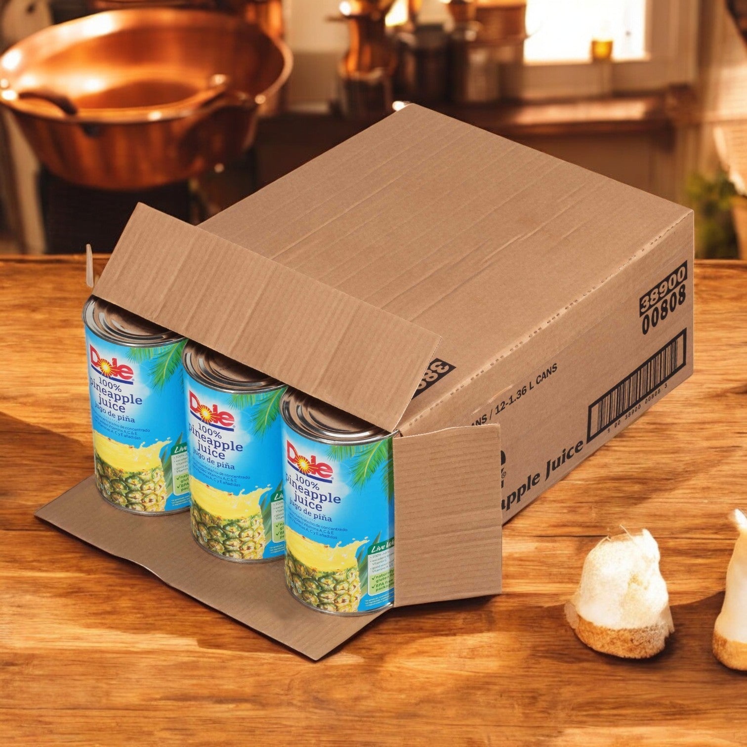 A cardboard box labeled "Dole Pineapple Juice, 46 oz. - 1 Case, 12 Pack" is open on a wooden kitchen counter.