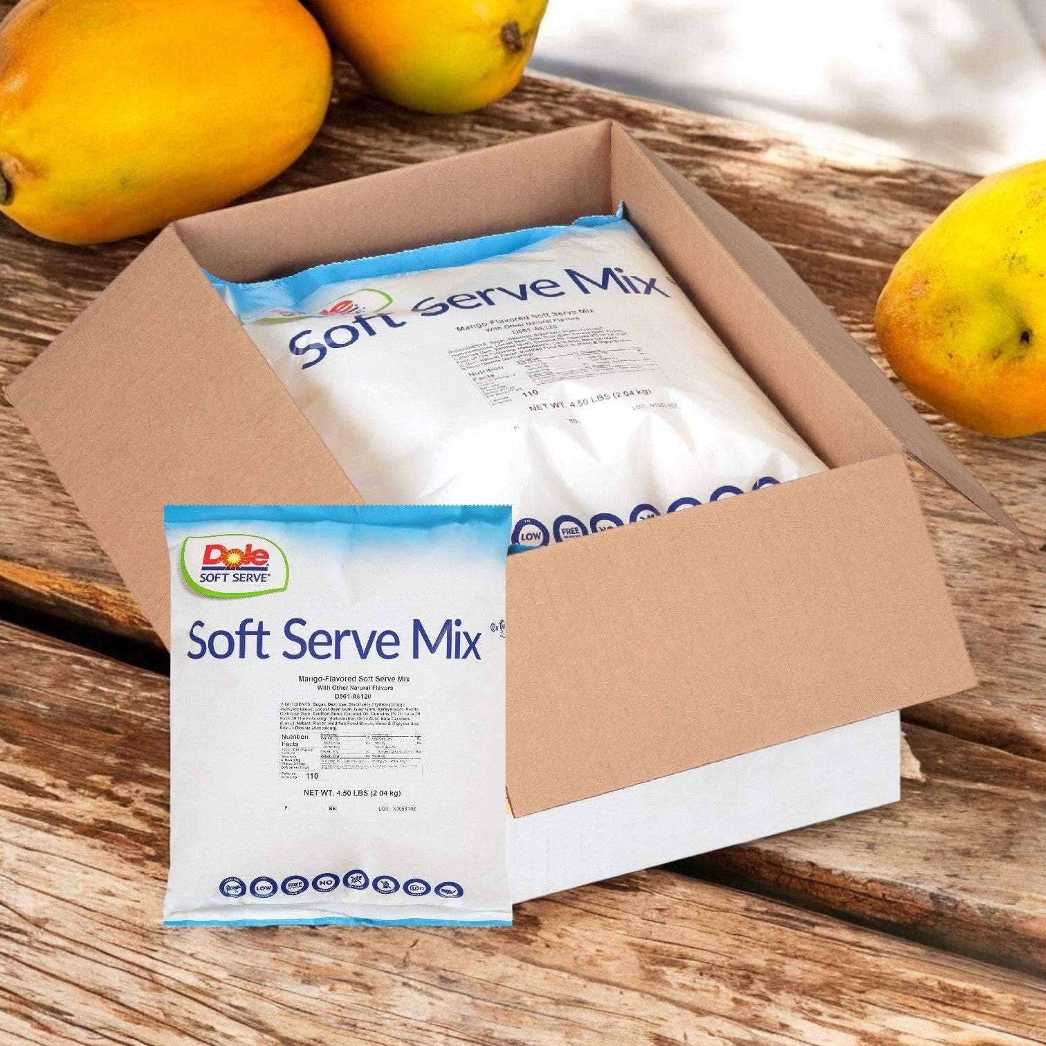 On a wooden surface, a bag from Dole's Soft Serve Mix Mango (4 bags of 4.5 lbs each) rests amidst ripe mangoes, offering a tropical flavor that promises a refreshing soft serve delight.