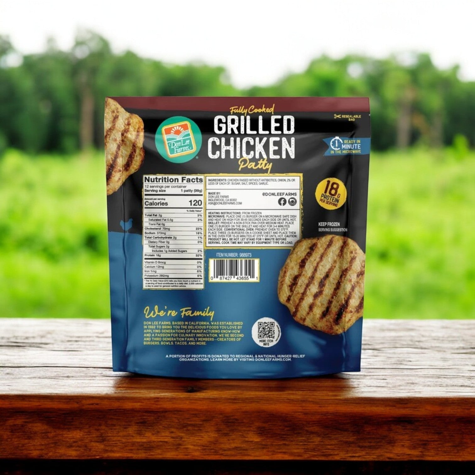 A package of Don Lee Farms Chicken Patties, 12-Count, is on a wooden table with a green field in the background. The all-natural, fully cooked patties packaging emphasizes nutrition facts and highlights their high protein content.