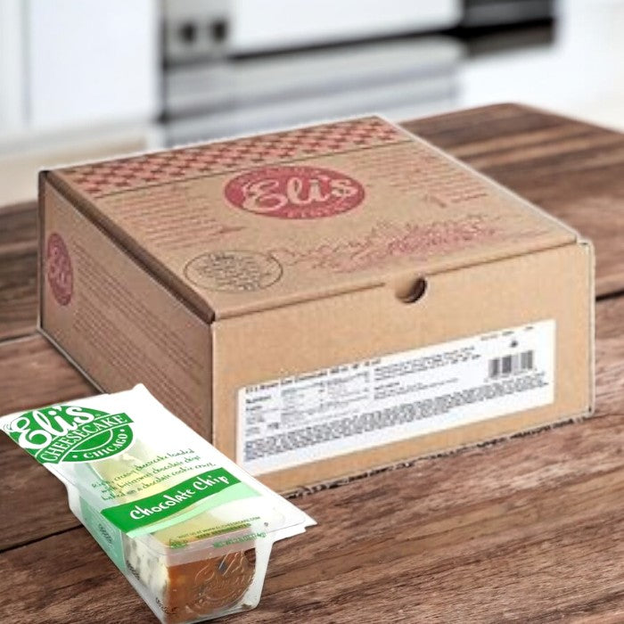 A brown cardboard box labeled "Eli's Cheesecake" sits on a wooden table. In front is a single-serve, wrapped slice of Eli's Cheesecake Chocolate Chip Cheesecake, offering indulgence in each bite.