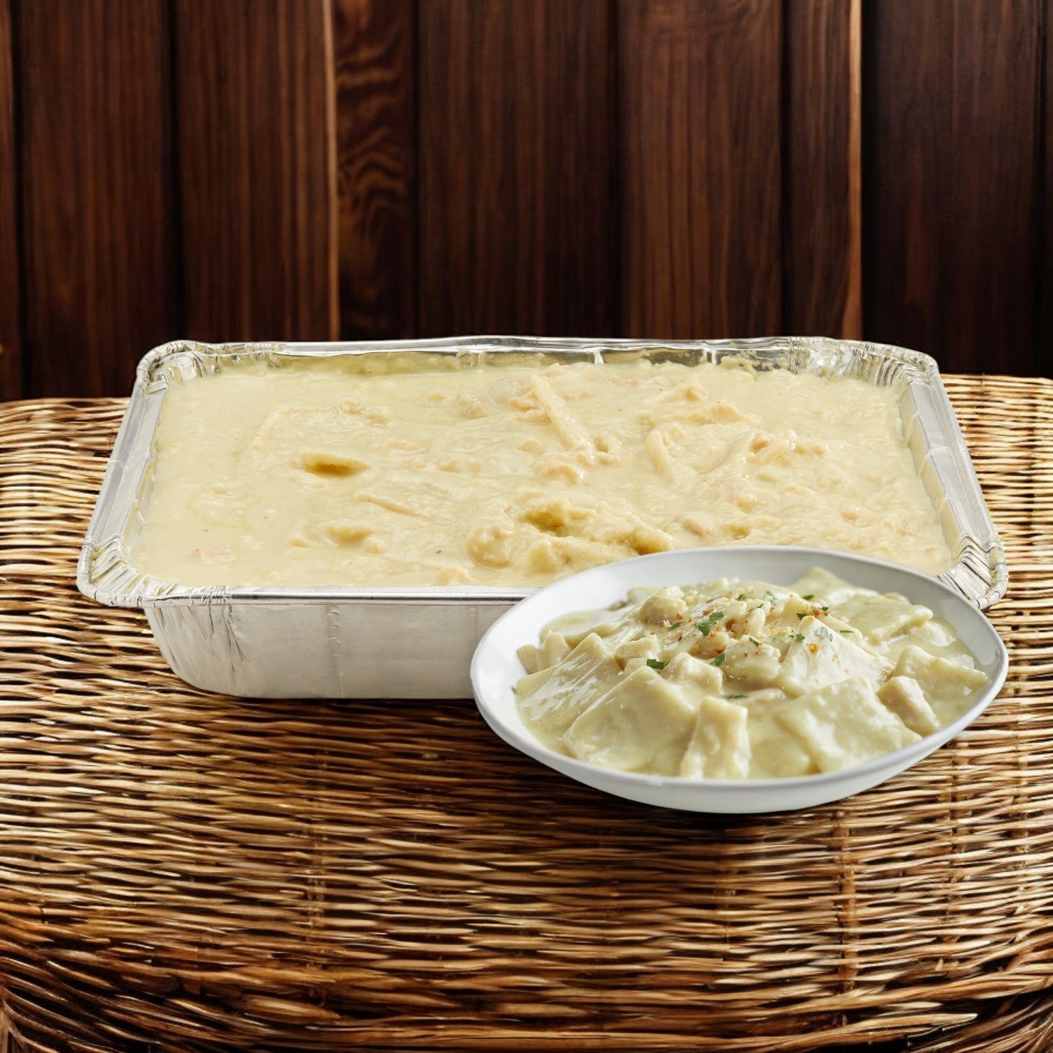 A Stouffer's Chicken and Dumpling tray from a case of 4 rests on a wicker surface with a round white bowl, set against a wooden background.