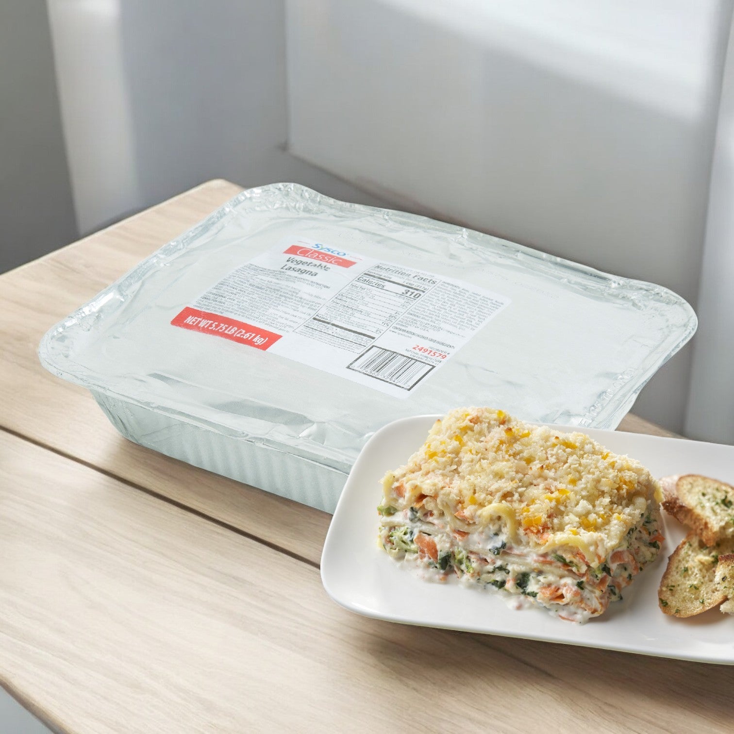 A Sysco Gilardi Calzone Meat Combo from a case of 60 rests on a wooden table, offering a convenient meal solution. In front, one calzone is served on a white plate with slices of bread, ready to be enjoyed.