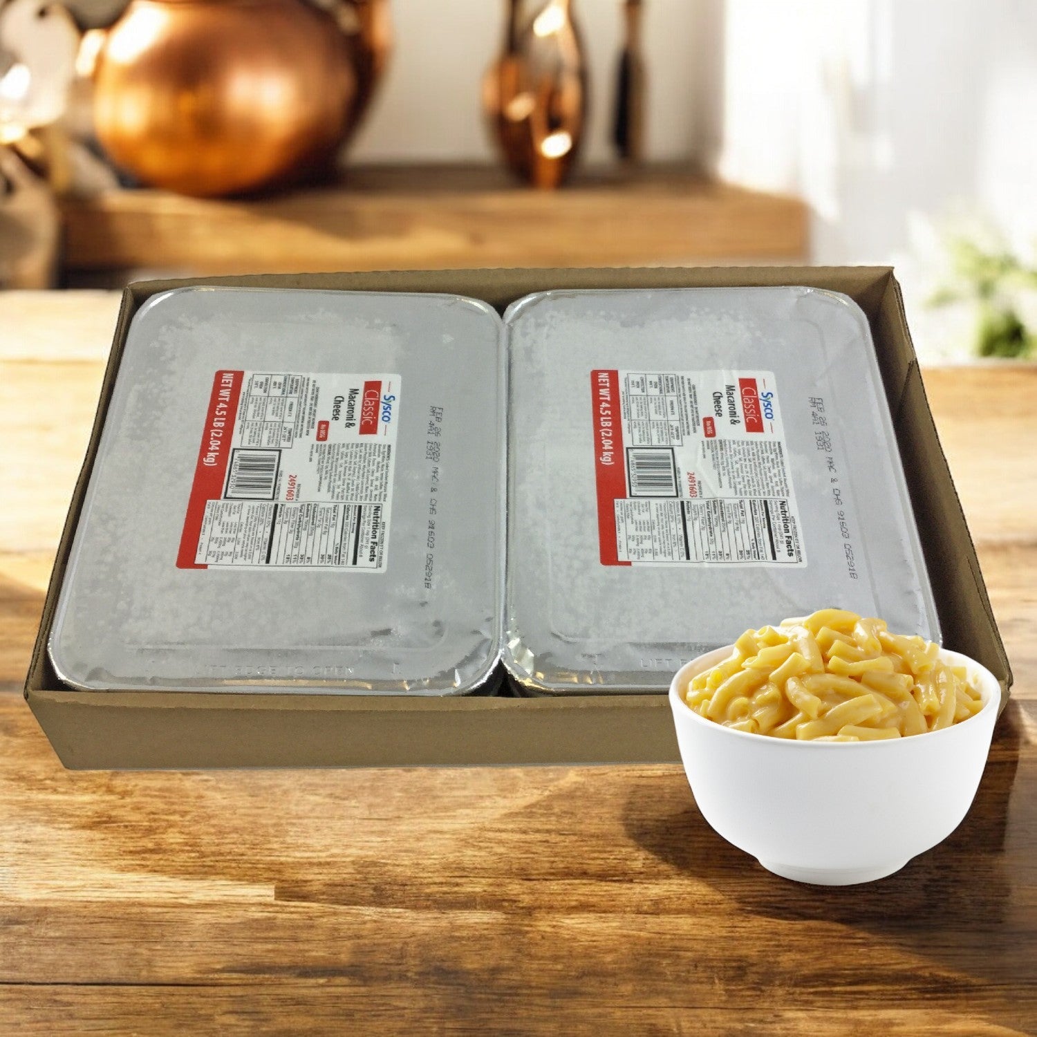 Two trays of Sysco Classic Entree Macaroni And Cheese, 4.5 lbs., rest on a table, showcasing rich and creamy flavors. A small bowl is ready for enjoyment. These trays offer hassle-free preparation to satisfy any comfort food craving.