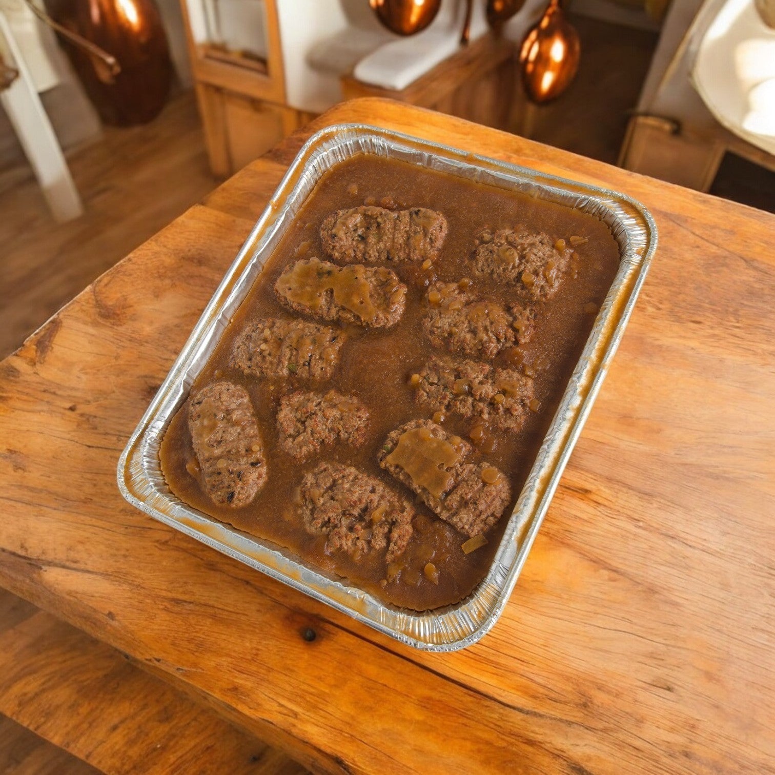 On a wooden table, an aluminum tray holds slices of Stouffer's Entree Meatloaf With Gravy from a 58 oz. pack, each slice covered in savory gravy.