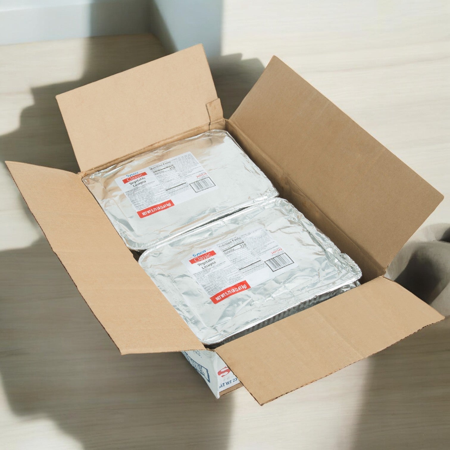 A Sysco Gilardi Calzone Meat Combo box holds two labeled foil food trays on a light surface, providing a convenient meal solution.