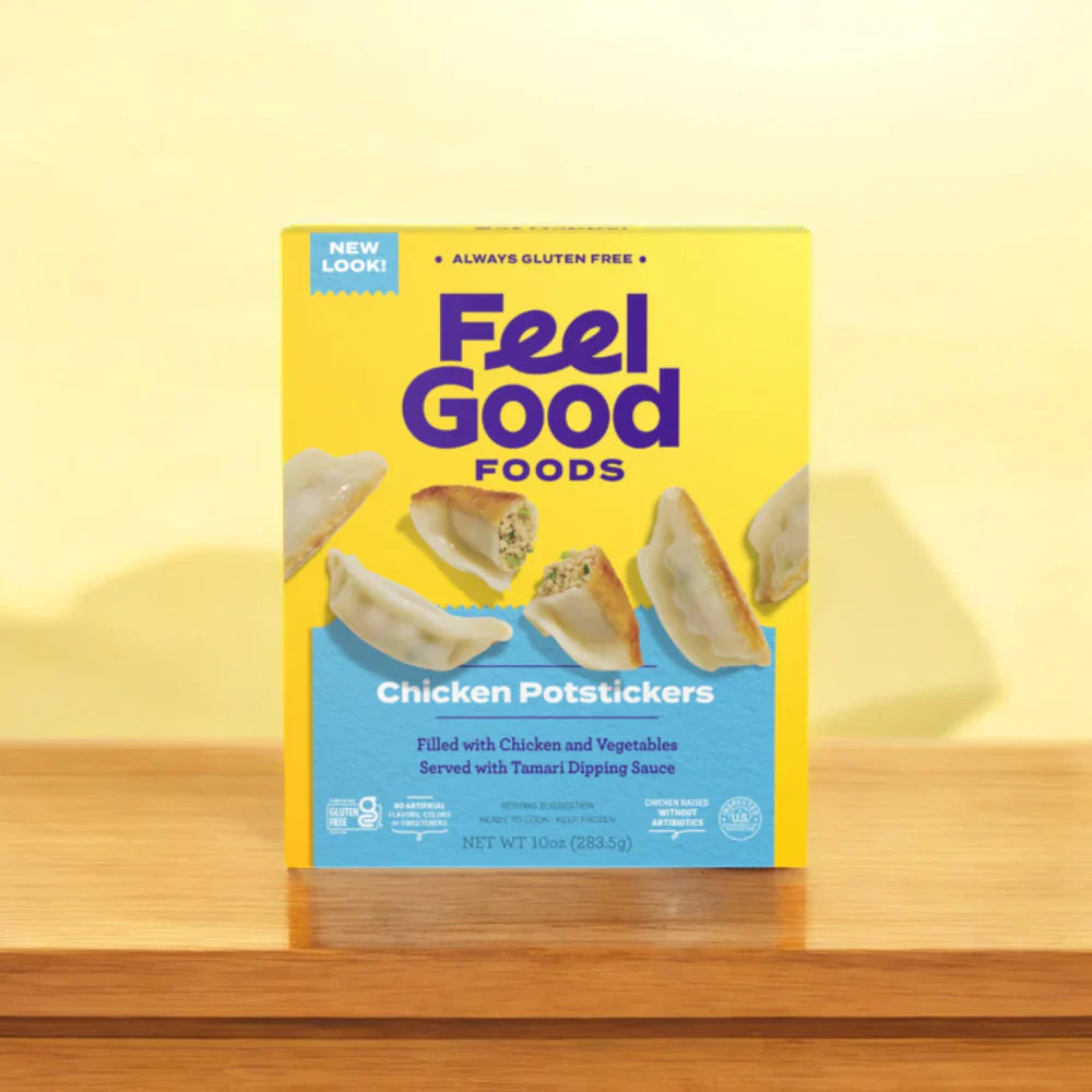 A box of Feel Good Foods Gluten-Free Bundle, featuring Potstickers, Egg Rolls, & Pizza Snacks, rests on a wooden surface against a yellow backdrop. The package’s potsticker image and dipping sauce offer a lighter alternative to those who love egg rolls.