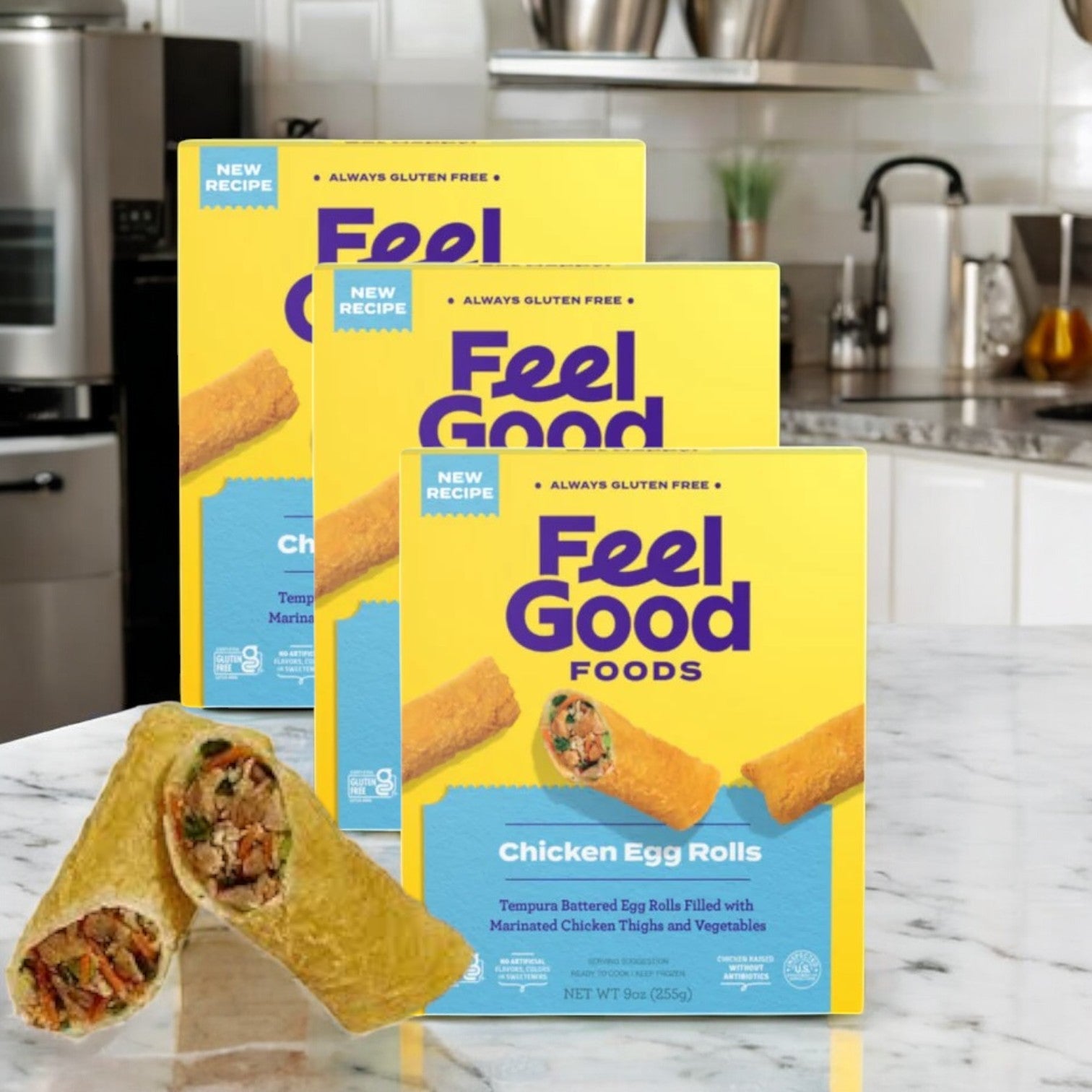Three boxes of Feel Good Foods Gluten-Free Chicken Egg Rolls, 9 oz., sit on a kitchen counter. One egg roll is cut open to reveal its savory filling. Ideal for a quick snack, these rolls offer convenience and taste whenever you crave a delicious bite.