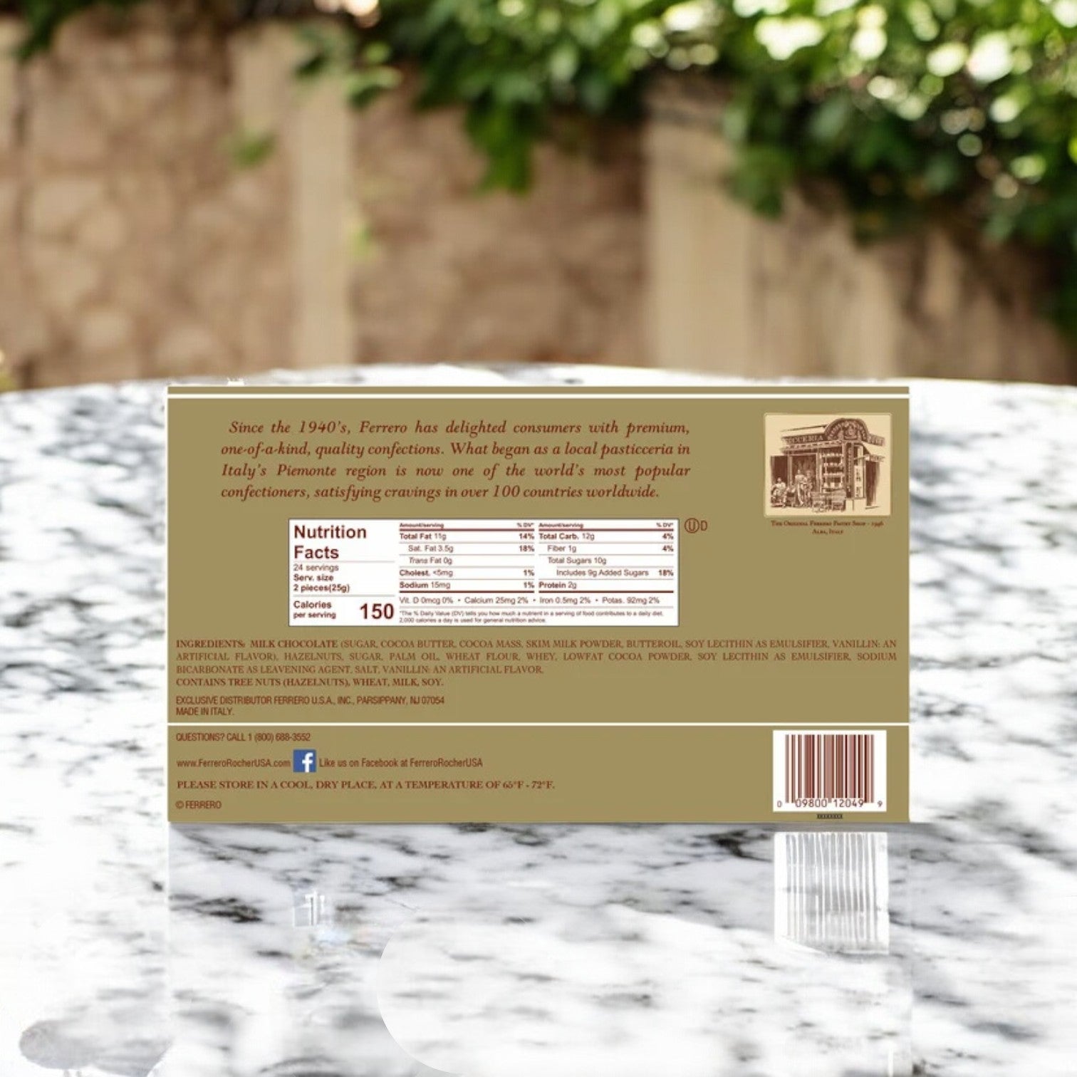 Ferrero Rocher Milk Chocolate Hazelnut Candy package on a marble surface, displaying nutritional info, ingredients like hazelnut candy, and a brief company history.