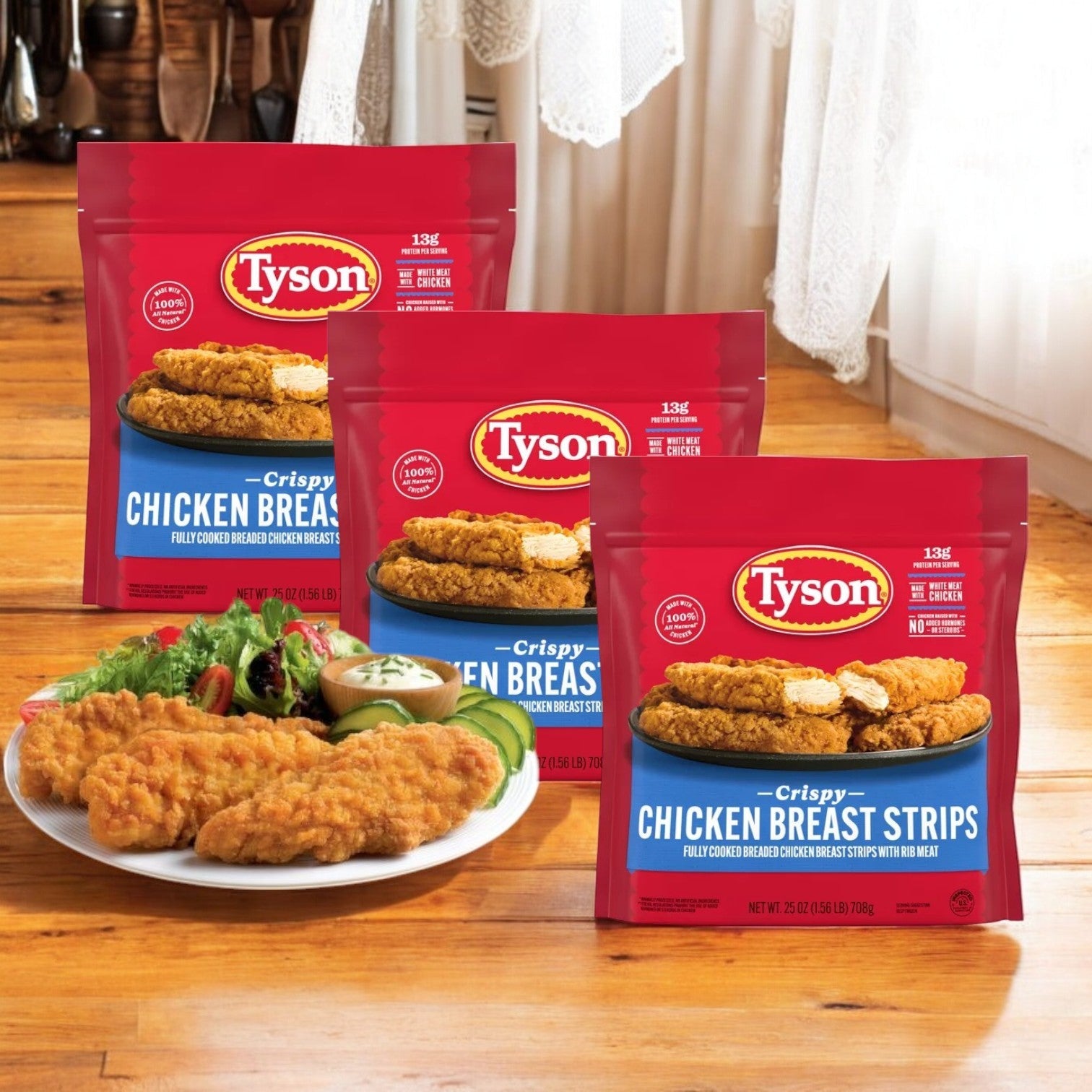Three bags of Tyson All Natural Crispy Chicken Strips – Frozen, 25 oz (3 Count) are shown behind a plate with the cooked strips and dipping sauces on a wooden table.