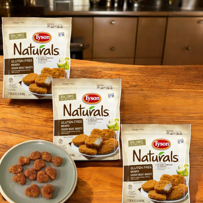 Three bags of Tyson Naturals Gluten Free Breaded Chicken Breast Nuggets, 20 oz., and a plate of crispy chicken nuggets rest on a wooden surface in a cozy kitchen setting.