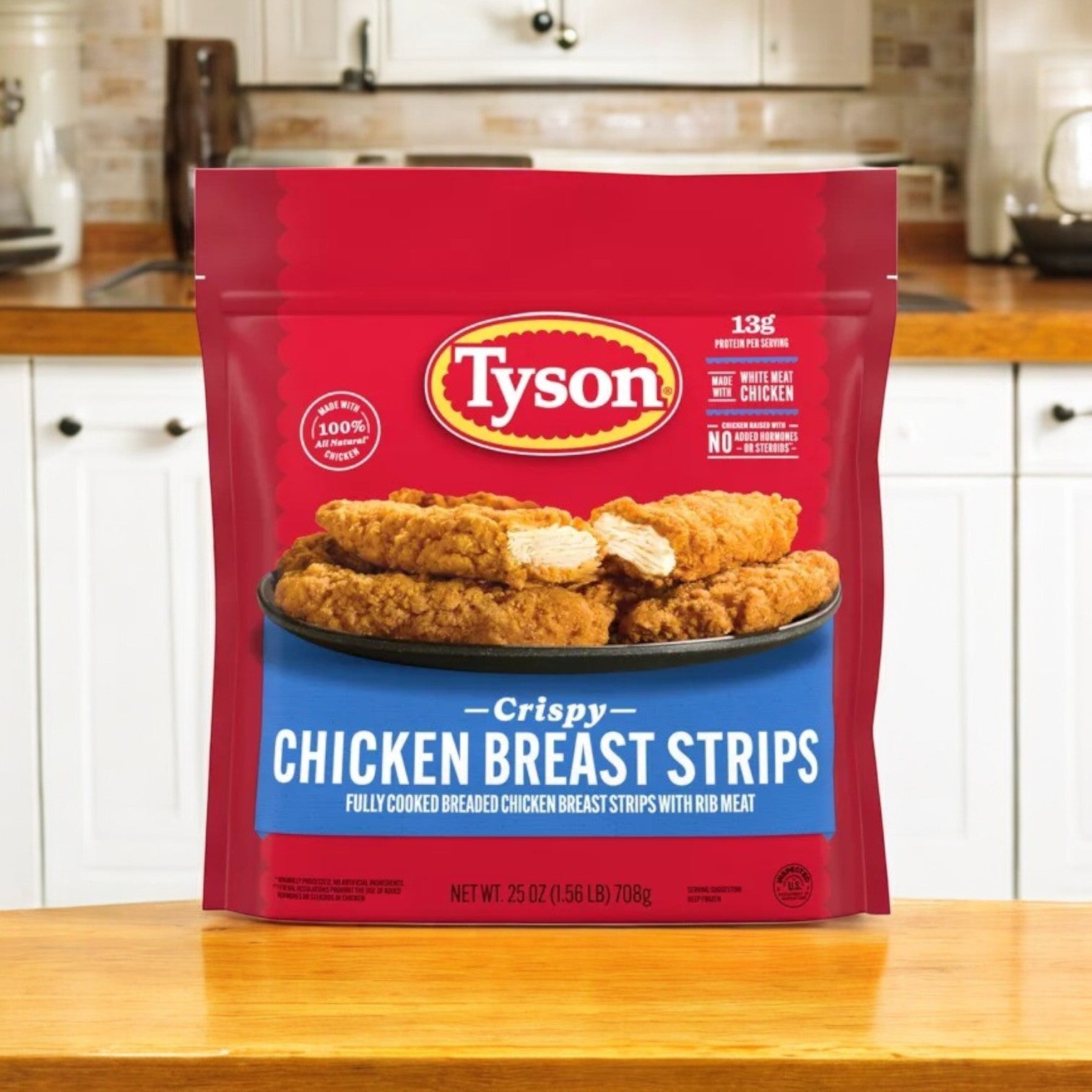 On the kitchen counter, a 25 oz bag of Tyson All Natural Crispy Chicken Strips – Frozen highlights its 100% all-natural chicken beside a plate of crispy breaded goodness.