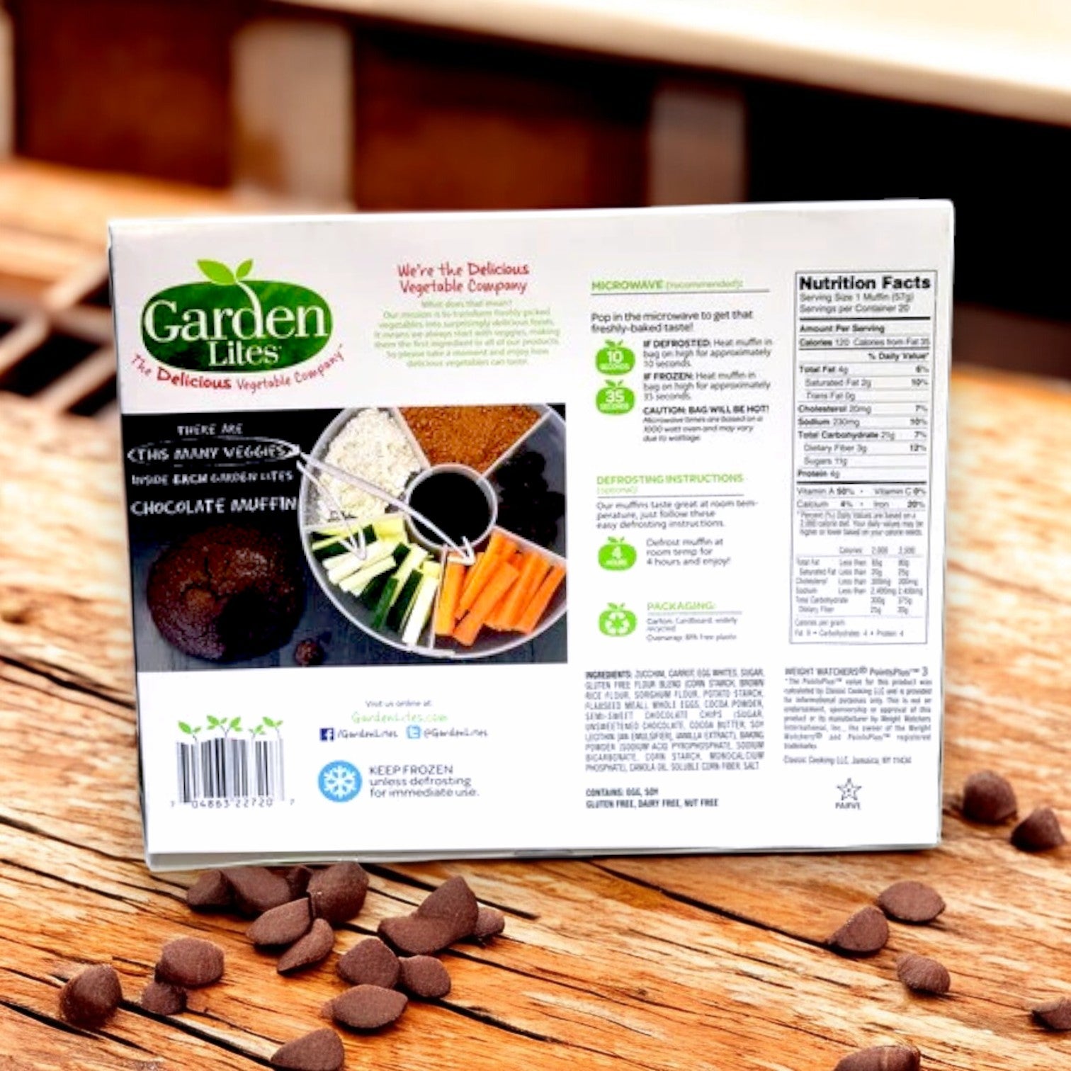 A Garden Lites Chocolate Muffins box by Veggies Made Great sits on a wooden table, showcasing dairy-free ingredients, cooking instructions, and nutrition facts. Labeled as gluten-free chocolate muffins with vegetables, they're a wholesome treat.