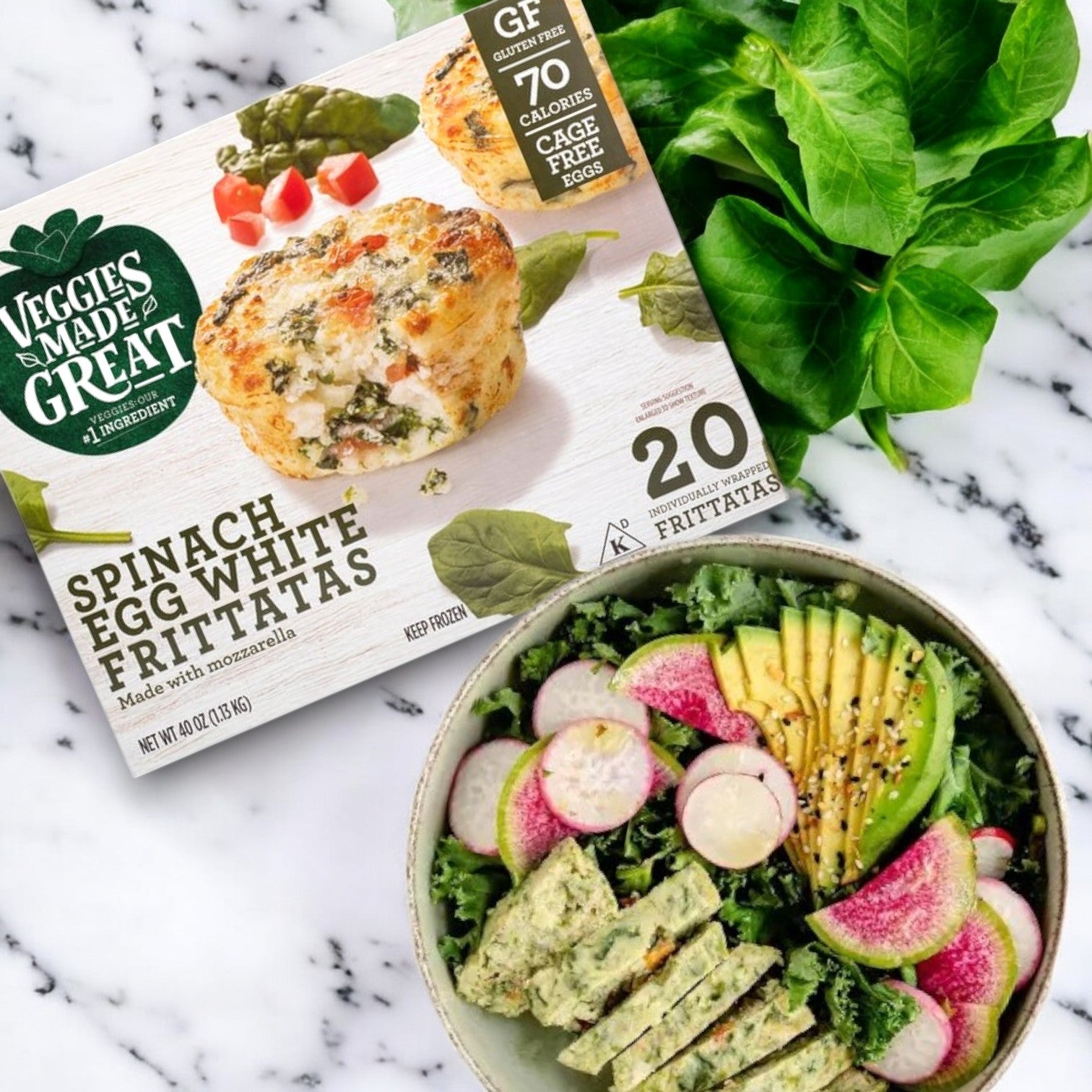 A box of Veggies Made Great Garden Lites Vegetarian Spinach & Egg White Frittatas (60-Count) sits beside a salad bowl packed with leafy greens, radishes, avocados, and sliced frittatas on a marble surface—ideal as a low-calorie snack or high-protein breakfast!.