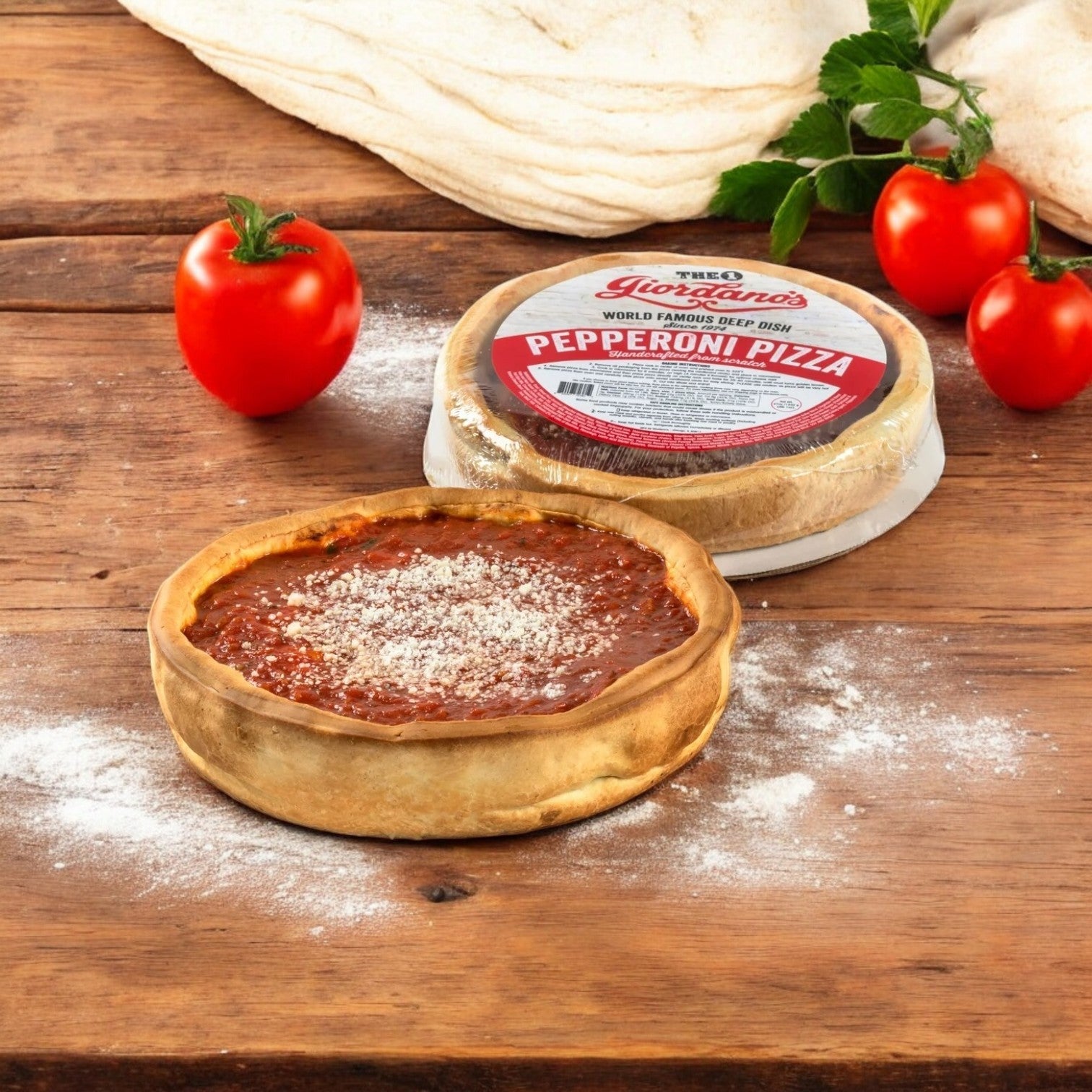 A Giordano's Frozen Deep Dish Stuffed Pepperoni Pizza, from a 10" three-pack, rests beside its box on wood, surrounded by fresh tomatoes and dough, capturing the authentic Chicago pizza essence.