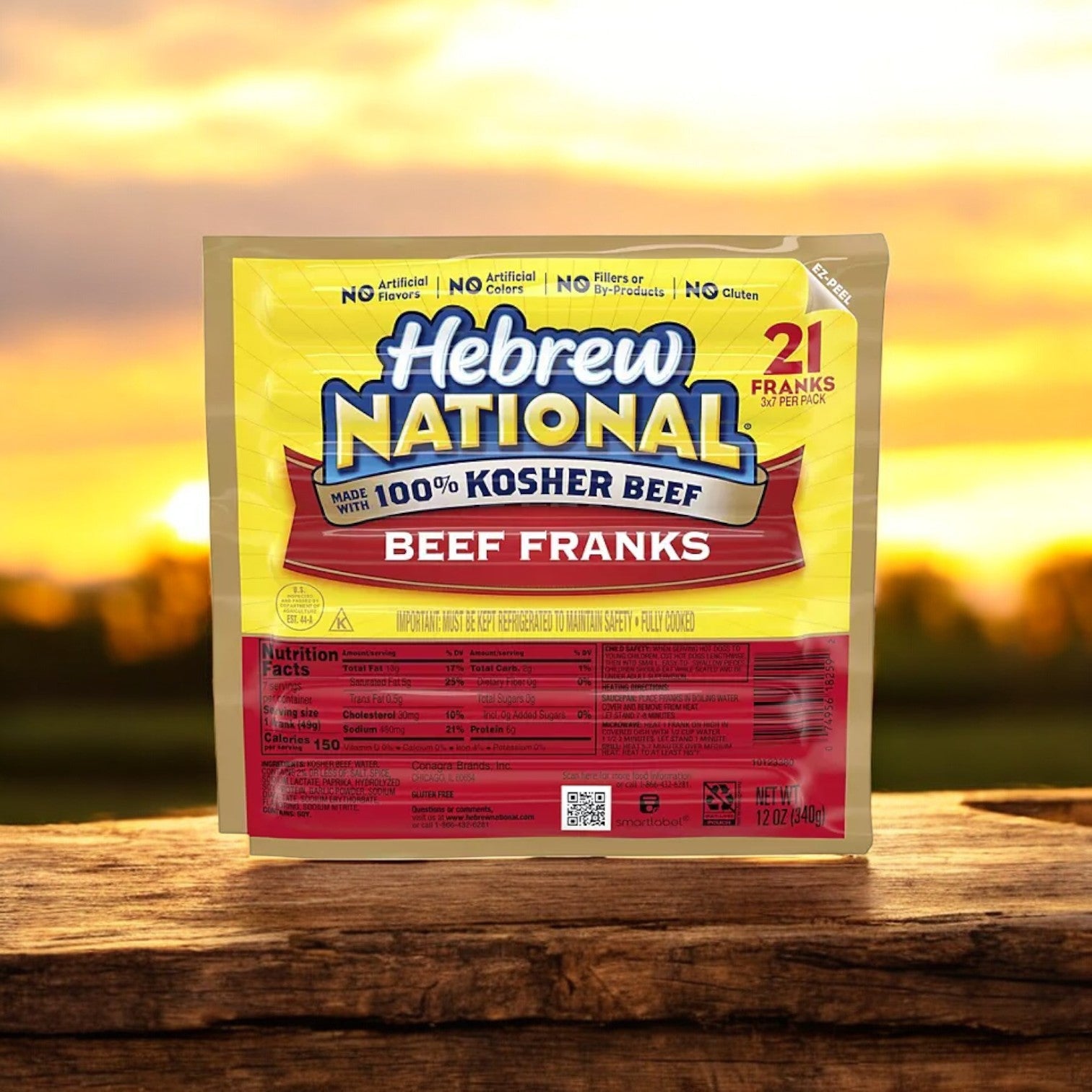 A pack of Hebrew National Beef Franks 12 oz., 3 ct. - 1 Pack rests on a wooden surface in the sunset glow. Made from 100% kosher beef, these premium hot dogs promise top-quality taste with every bite.