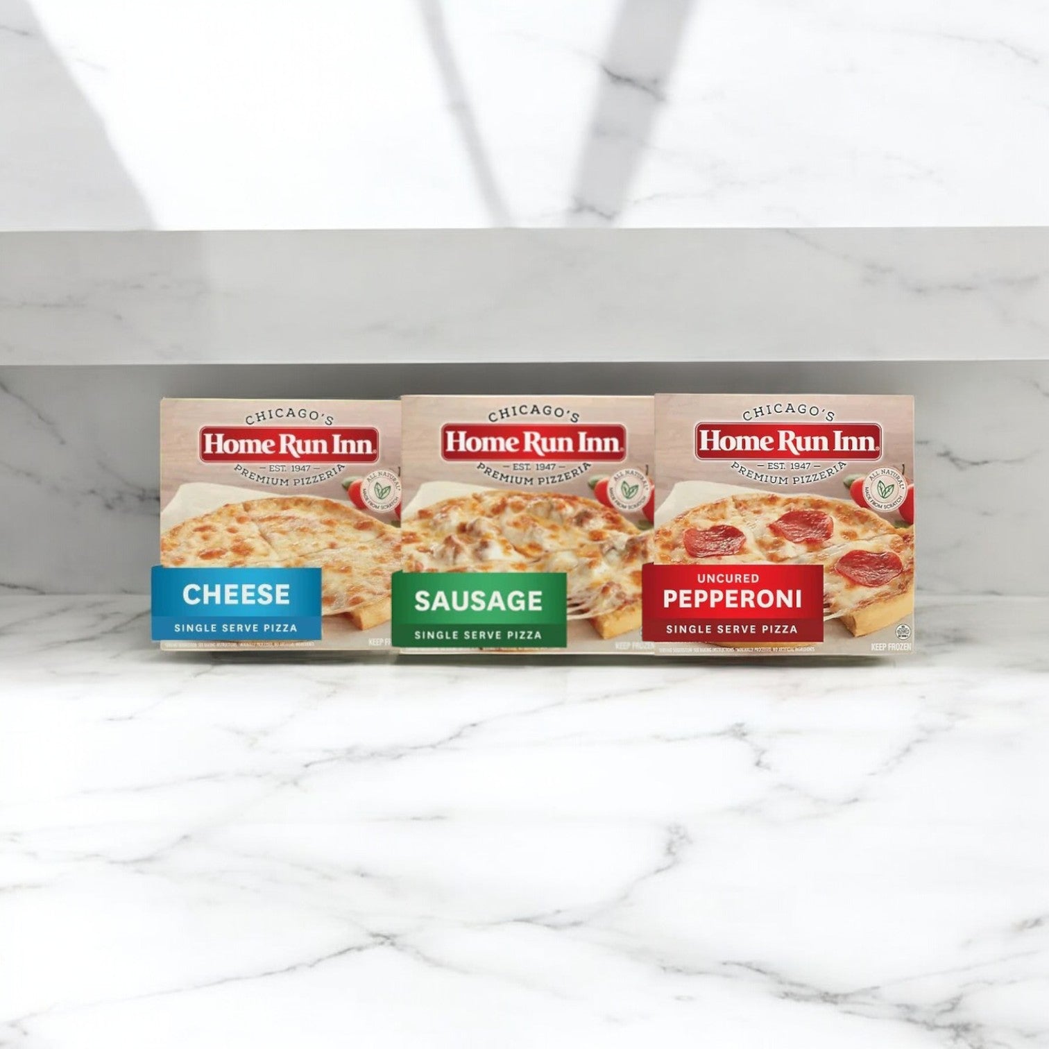 On a marble surface, there's a Home Run Inn 6-Pack Pizza Combo featuring family-sized and single-serve pizzas: cheese, sausage, and uncured pepperoni. Ideal for cozy family gatherings or quick solo meals.