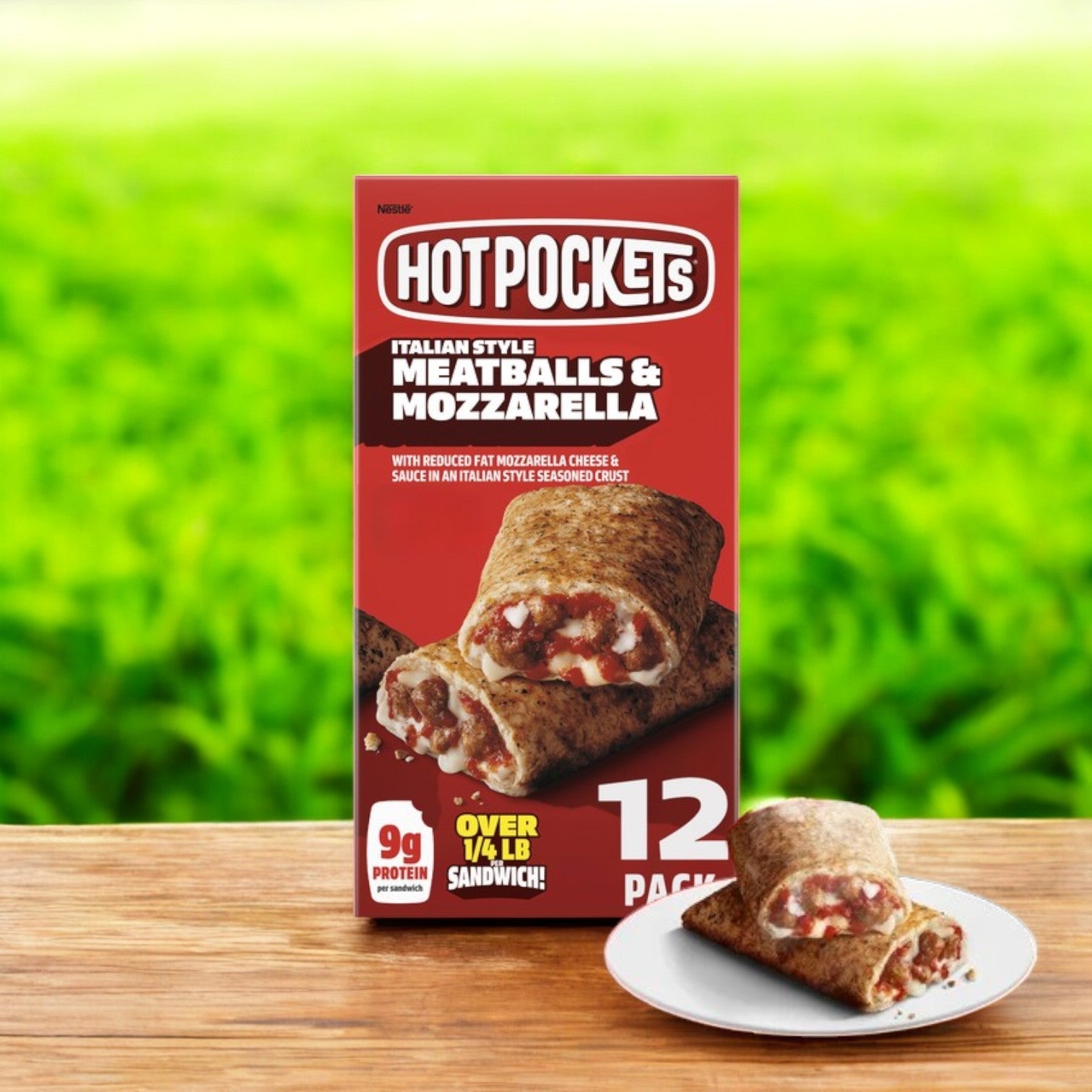 A box of Hot Pockets Italian Style – 12 Count rests on wood beside a plate with one Hot Pocket, offering a savory variety. A grassy backdrop enhances this appetizing view.