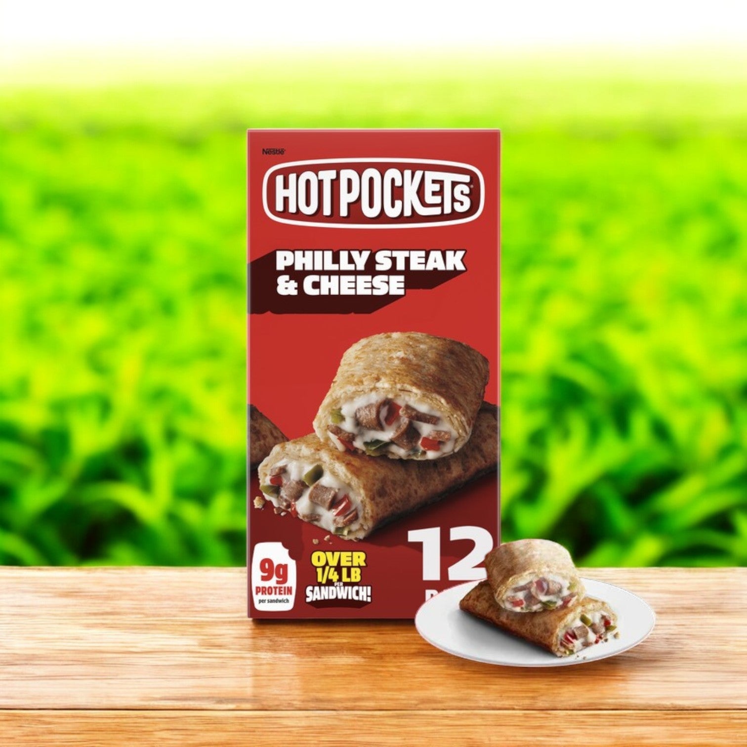 A box of Hot Pockets Philly Steak and Cheese – 12 Count by Hot Pockets is on a wooden surface, with a prepared pocket filled with Italian-inspired ingredients on a plate, set against a blurred green background.