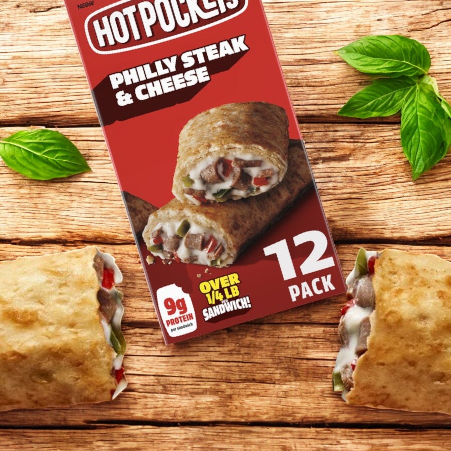 Hot Pockets Philly Steak and Cheese – 12 Count box on a wooden surface, showcasing open sandwiches filled with seasoned meat, mozzarella cheese, and peppers. Basil leaves are arranged beside for added freshness to the Italian-inspired flavor.