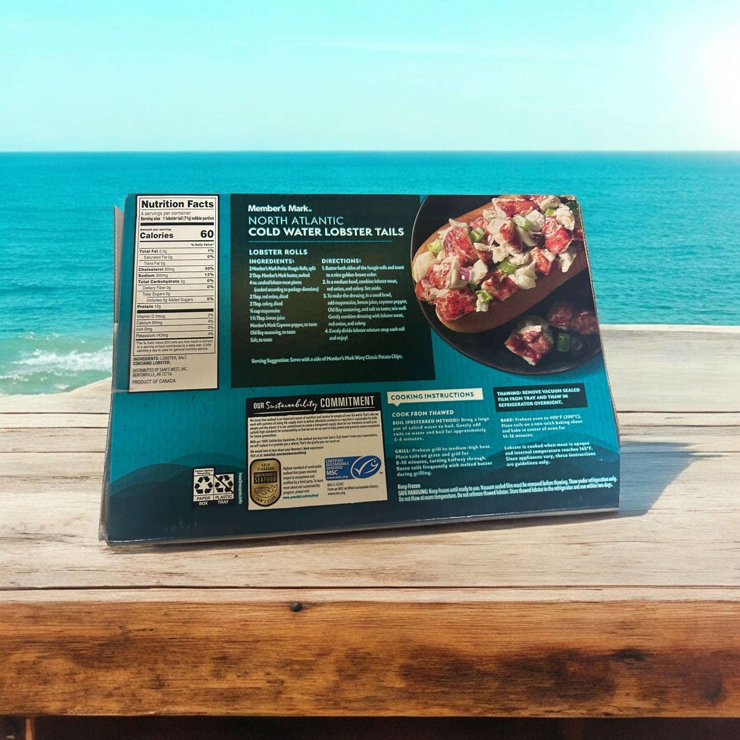 Member's Mark Cold Water Lobster Tails, Frozen, 4 Count, 3 Packs are displayed on a wooden table with a beach and ocean view. The box provides nutrition facts and cooking instructions to enhance your dining experience with every savor of these North Atlantic delights.
