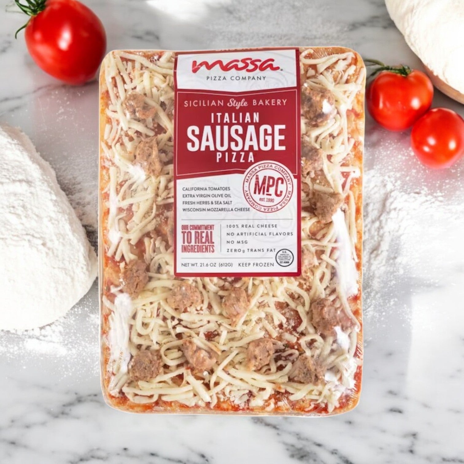 On a marble surface, surrounded by tomatoes and a heap of flour, the Massa Pizza Co. 3 Pack Combo! from Massa Pizza features an artisan bakery crust that enhances every savory bite of its Sicilian Bakery Italian Sausage Pizza.