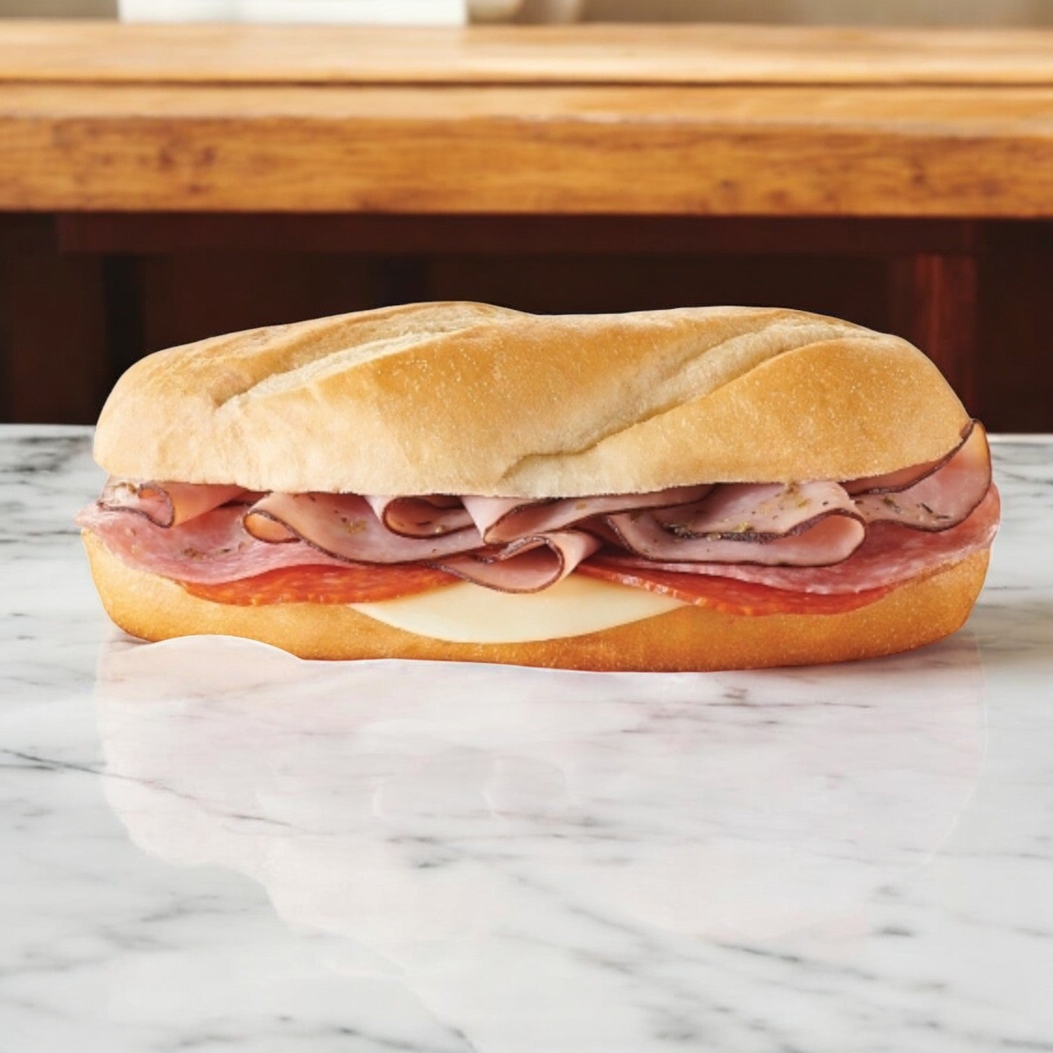 An E.A. Sween Italian Style Sub, with Italian cold cuts and provolone cheese, sits on a white marble surface. It's shipped frozen and has a 30-day shelf life in the cooler after defrosting.