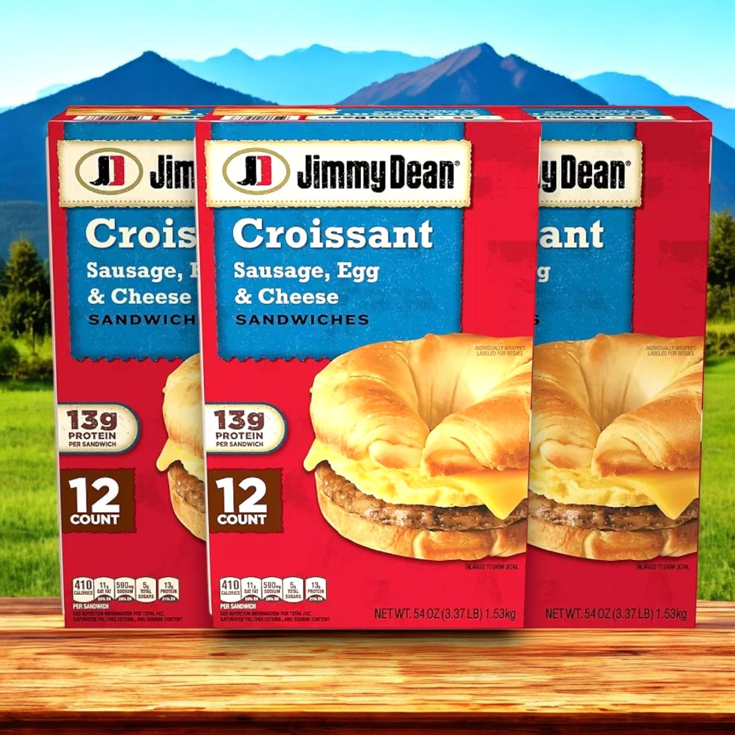 Jimmy Dean Sausage, Egg & Cheese Croissant Sandwiches, in packs of 12 totaling 36 sandwiches, are displayed in front of a mountain landscape.