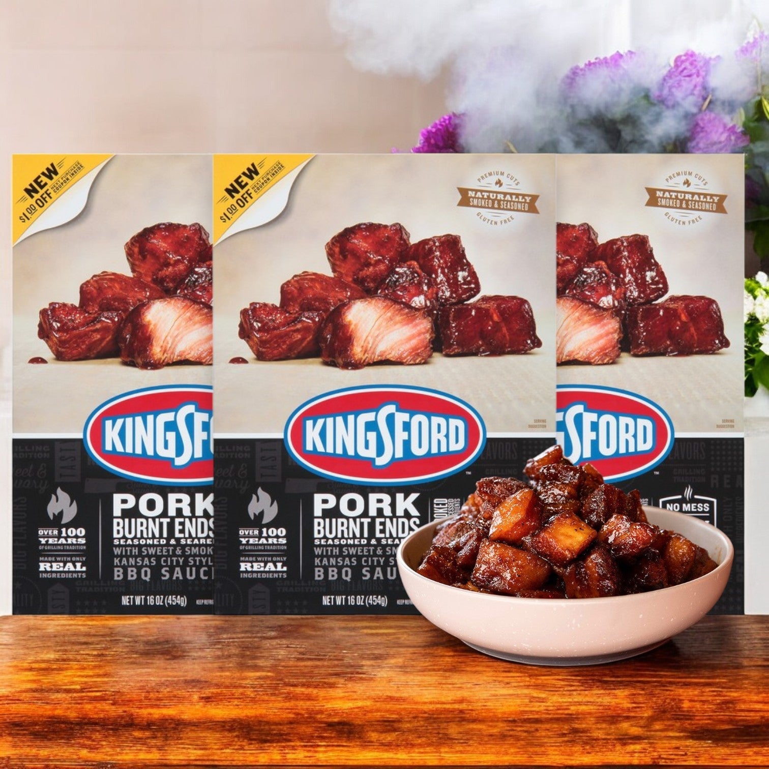 Kingsford Pork Burnt Ends – Seasoned & Seared, 16 oz.-3 Count boxes are showcased behind a bowl of the cooked product, offering a rich, smoky BBQ flavor that embodies outdoor grilling.