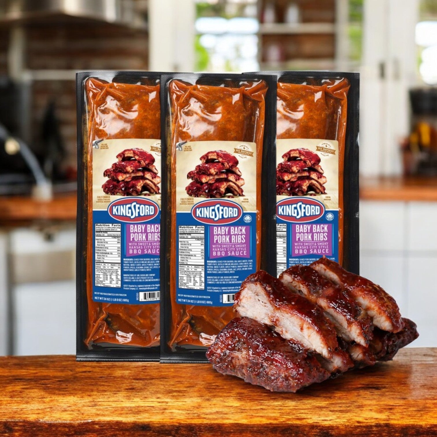 Three packs of Kingsford Baby Back Pork Ribs, coated in Sweet & Smoky Kansas City BBQ Sauce, are set on a wooden surface with some saucy ribs showcased in front.