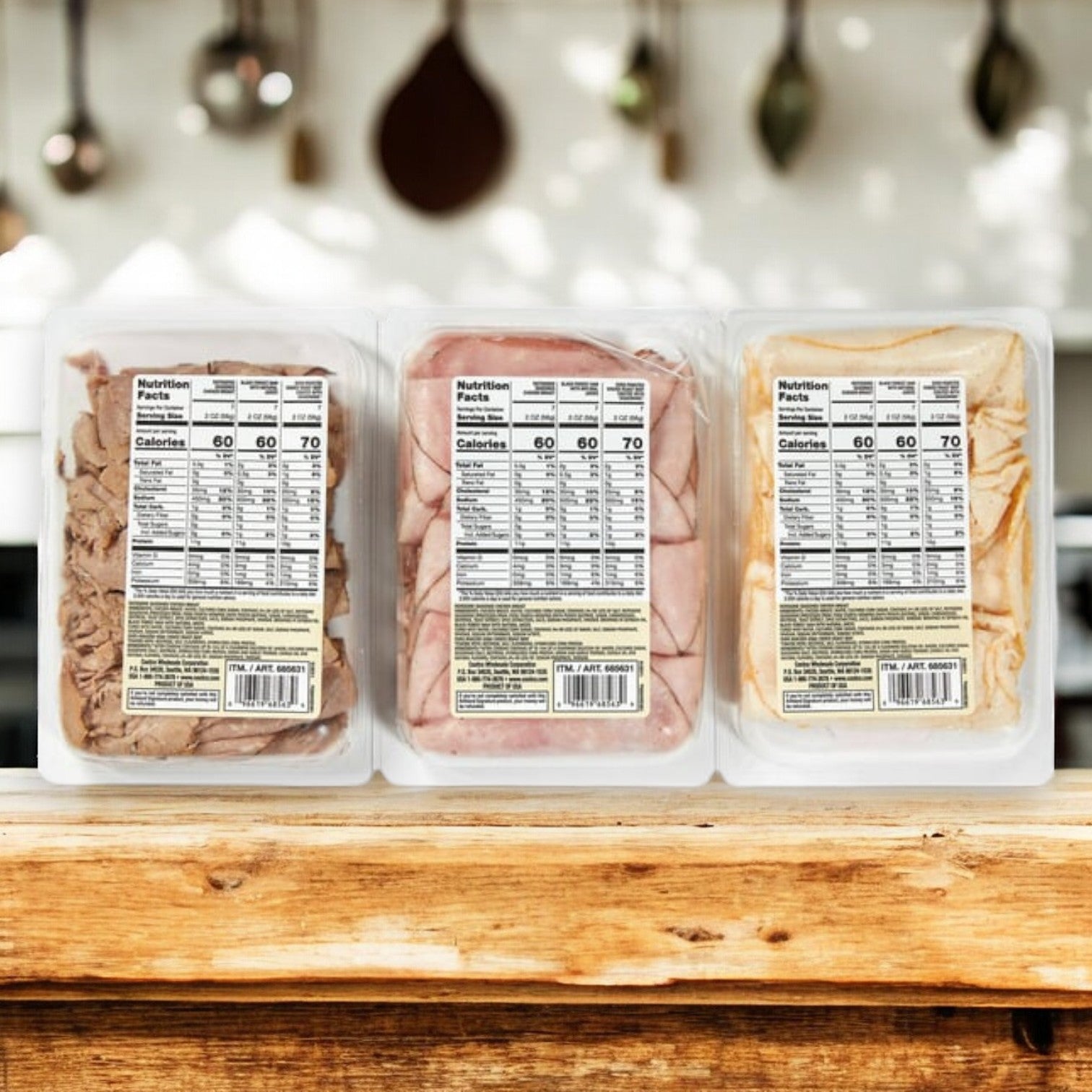 The Kirkland Signature Variety Lunch Meat Pack, featuring three 14 oz packs, is displayed on a wooden kitchen surface, ideal for creating protein-rich charcuterie boards.