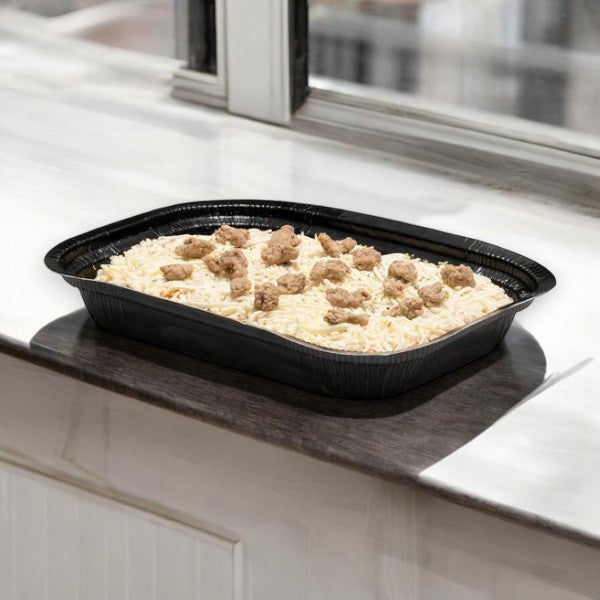 A black tray containing Kirkland Signature Italian Sausage and Beef Lasagna, with layers of premium ingredients, including succulent pieces of sausage, sits conveniently on a windowsill.
