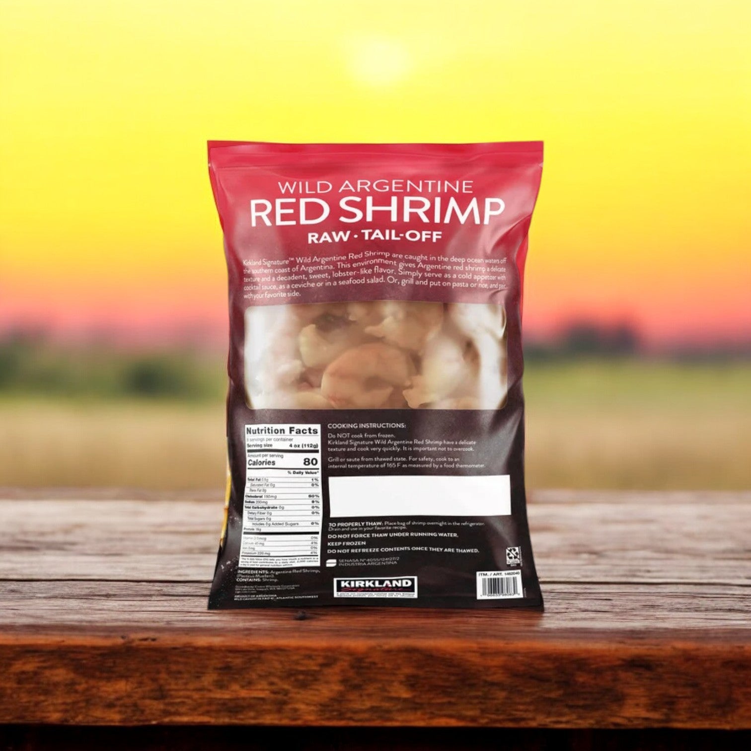 A package of Kirkland Signature Wild Argentine Raw Shrimp, consisting of three 2-pound bags for a total of 6 pounds, is displayed on a wooden surface. The packaging highlights its premium taste and eco-friendly sourcing, complete with comprehensive nutritional details and cooking instructions set against a lively backdrop.