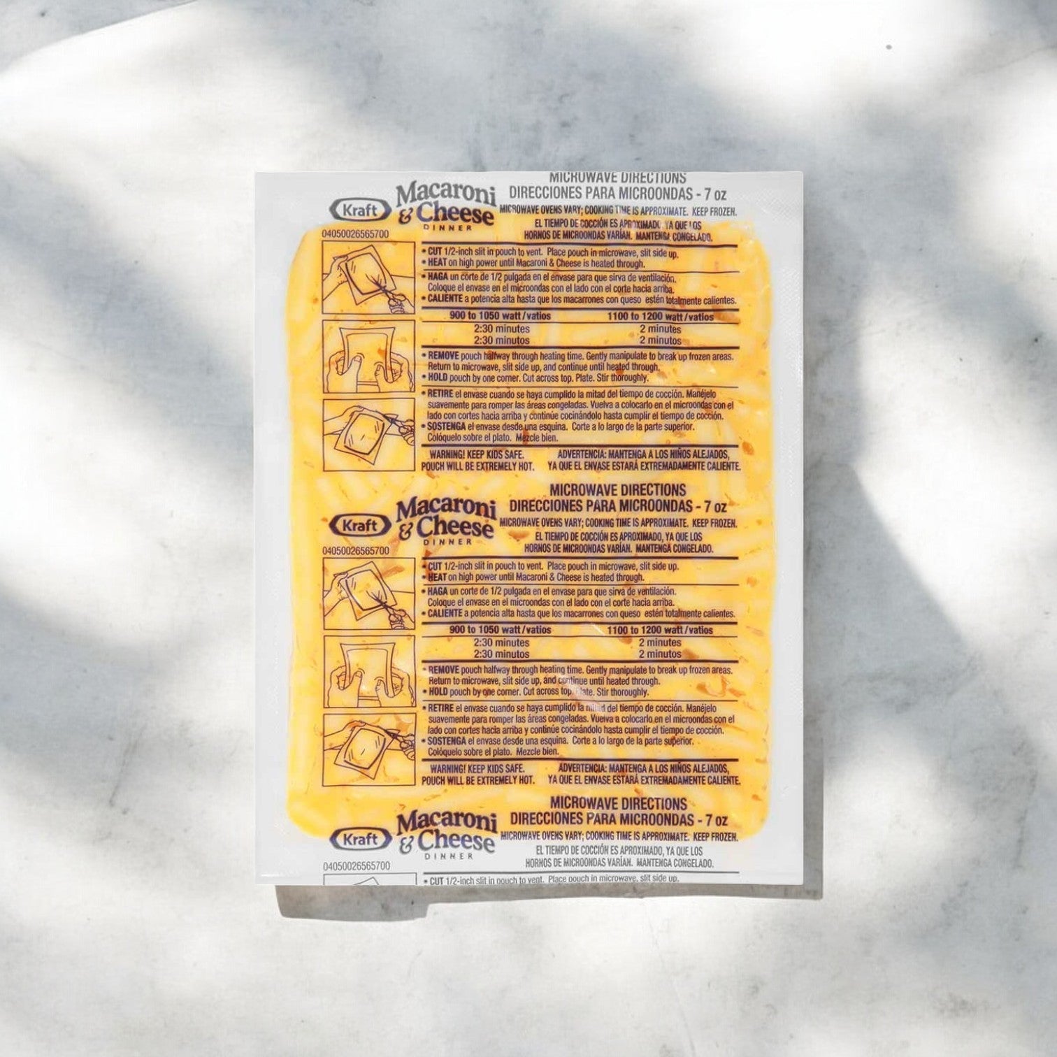 The Kraft Frozen Entree Macaroni and Cheese 7 oz. box (36 packs) features cooking instructions and illustrations in English and Spanish on the back, set against a white background, highlighting its creamy cheese sauce.