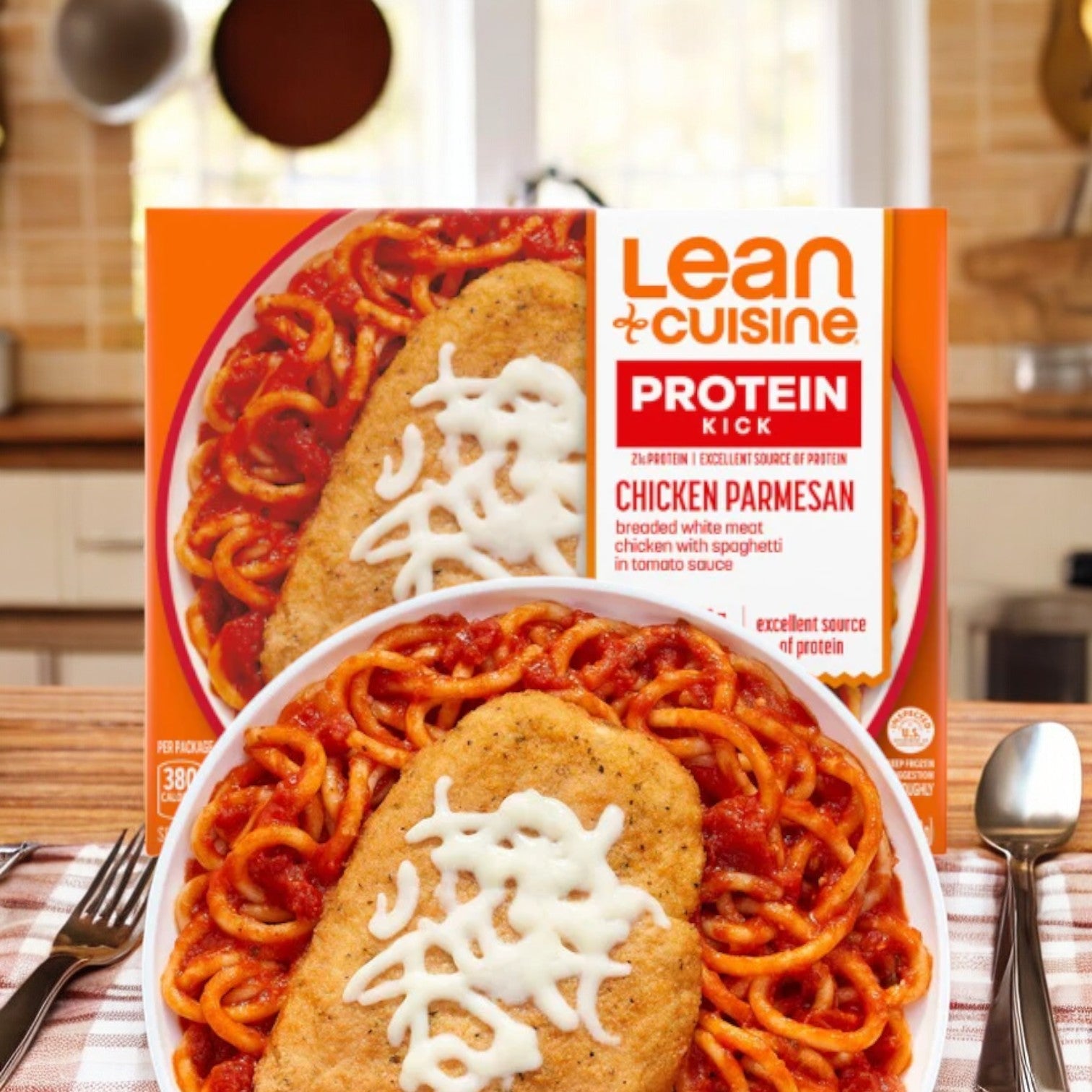A box and plate of Lean Cuisine Chicken Parmesan, featuring breaded chicken breast with spaghetti in tomato sauce topped with cheese, are elegantly arranged on a kitchen table, presenting a savory Italian meal for a delightful dining experience.