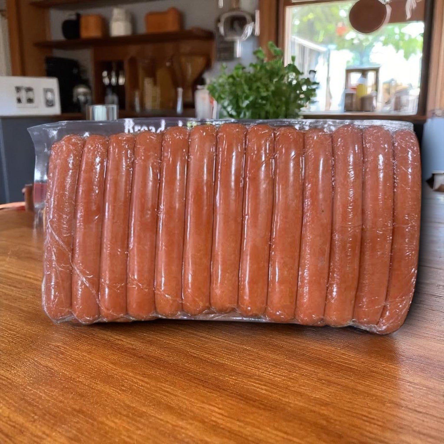 A 5 lb sealed plastic pack of Endless Market Leon's Sausage 8:1 Halal Beef Hot Dogs, containing 40 hot dogs, sits on a wooden table with a kitchen in the background.