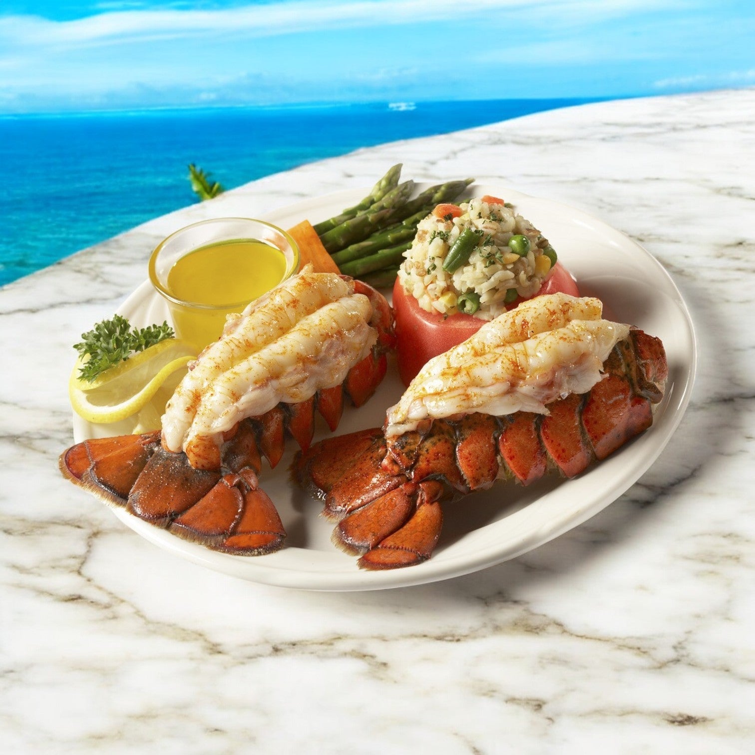 Atlantic Premium's Lobster Tail North Atlantic Premium, grilled with butter and a lemon wedge, is served with asparagus and vegetable rice on a white plate. The meal sits on a marble surface with a stunning North Atlantic ocean view in the background.